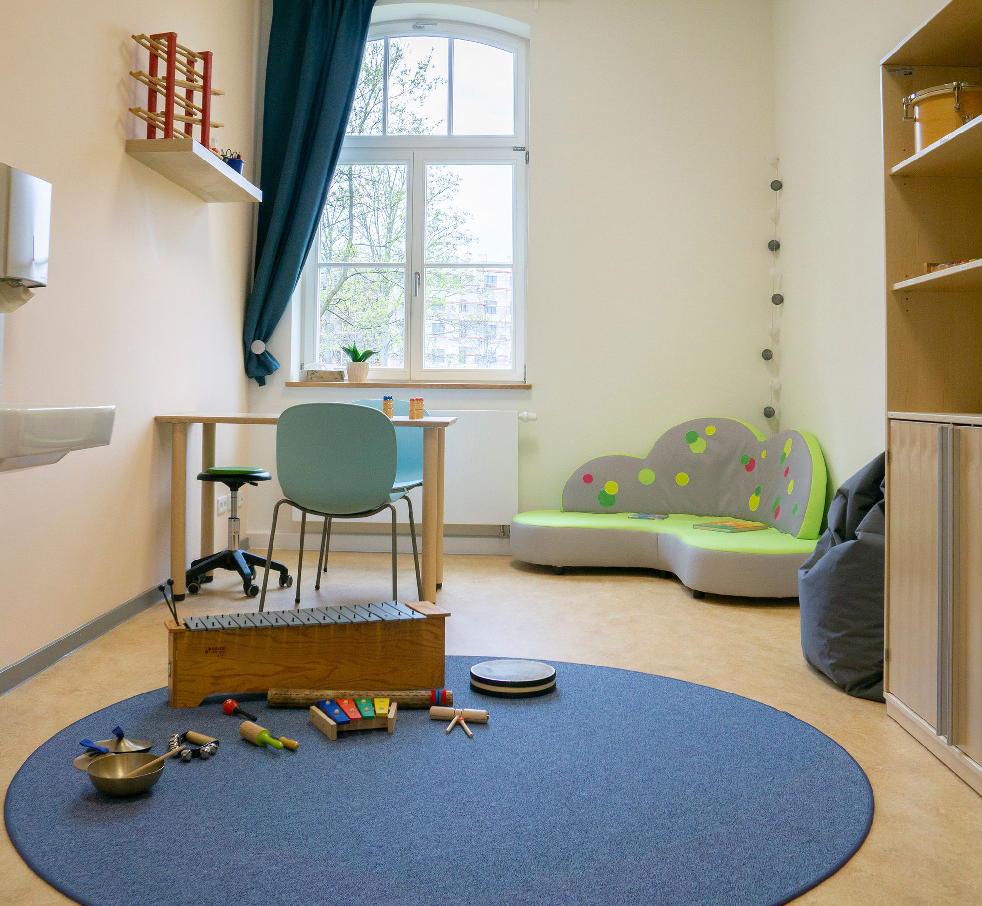 Ein Raum mit Musikinstrumenten, kleinem Sofa, Tisch und Stühlen.