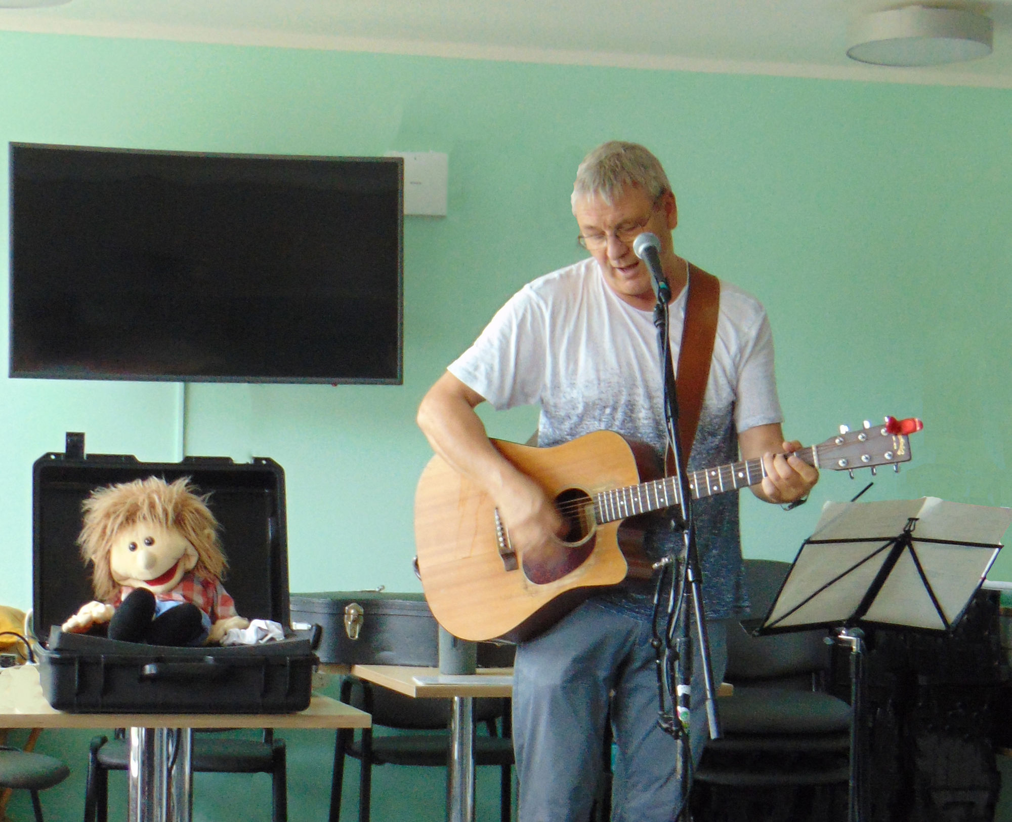 Ein Mann mit Gitarre singt in ein Mikrofon.