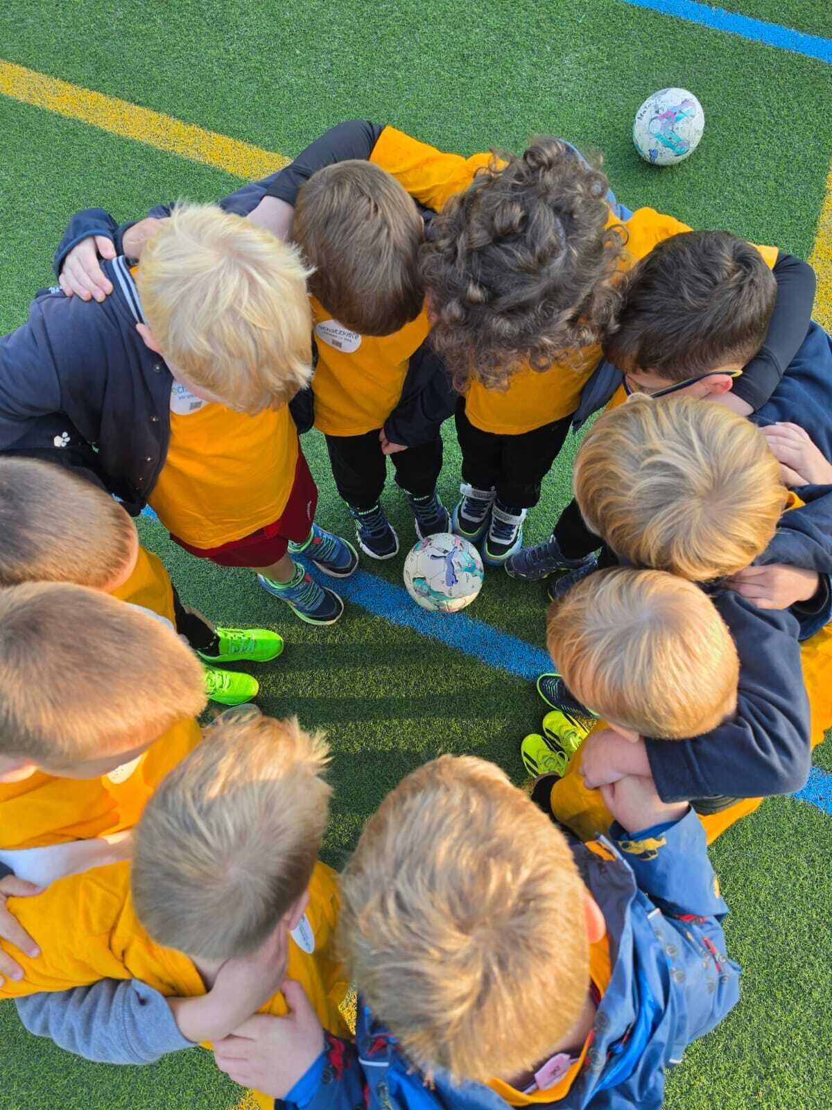 Kinder stehen geschlossen im kreis und haben die Arme auf den Schultern der anderen