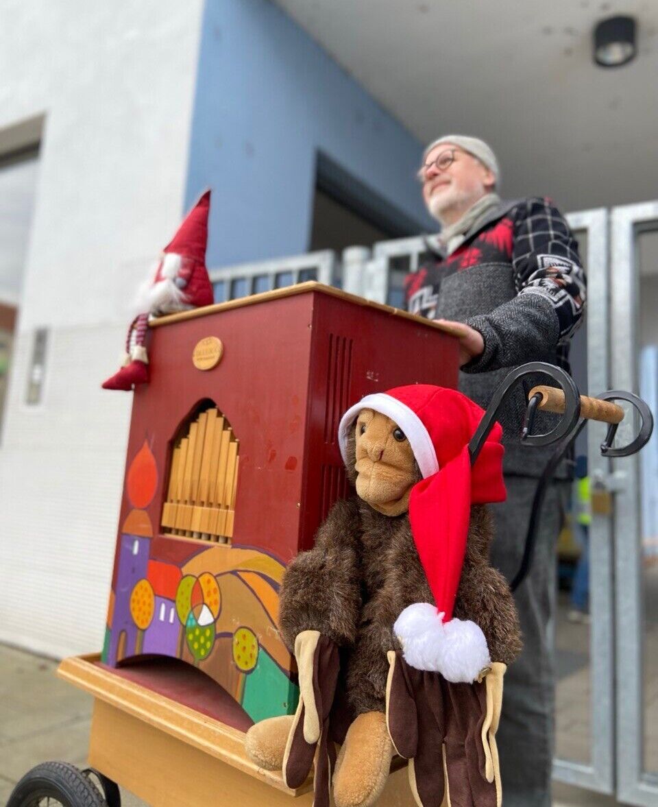 Ein Affe aus Pl&uuml;sch sitzt neben Leierkasten