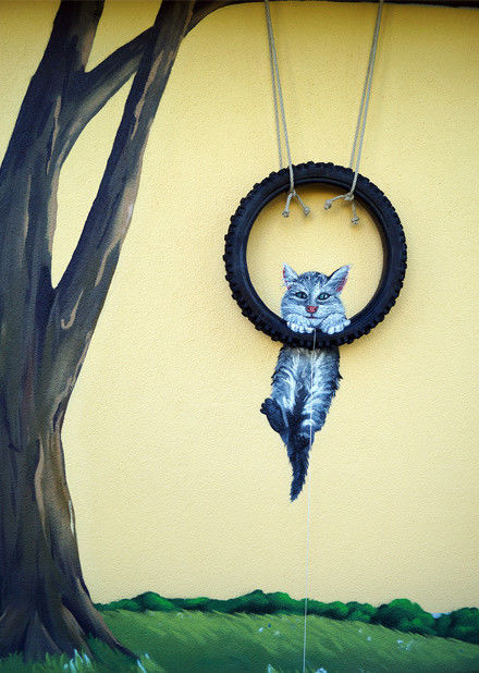 Eine bemalte Außenfassade mit Baum und Katze.