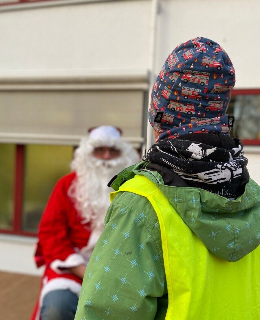 Ein Kind mit gelber Leuchtweste schaut einen Weihnachtsmann an