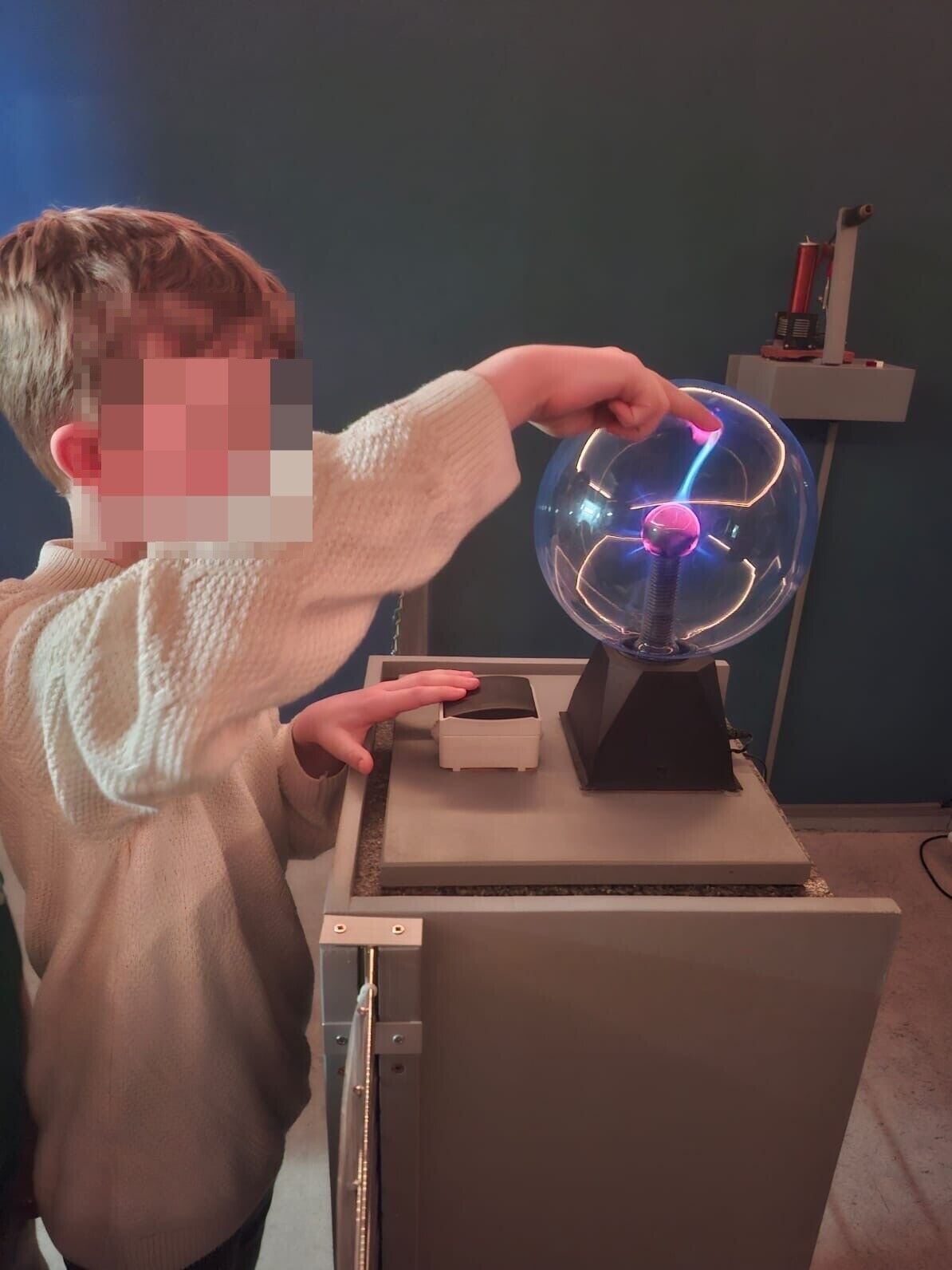 © SEB Leipzig Ein Junge hält den Finger auf eine Glaskugel. Bunte Lichtblitze treffen auf den Finger