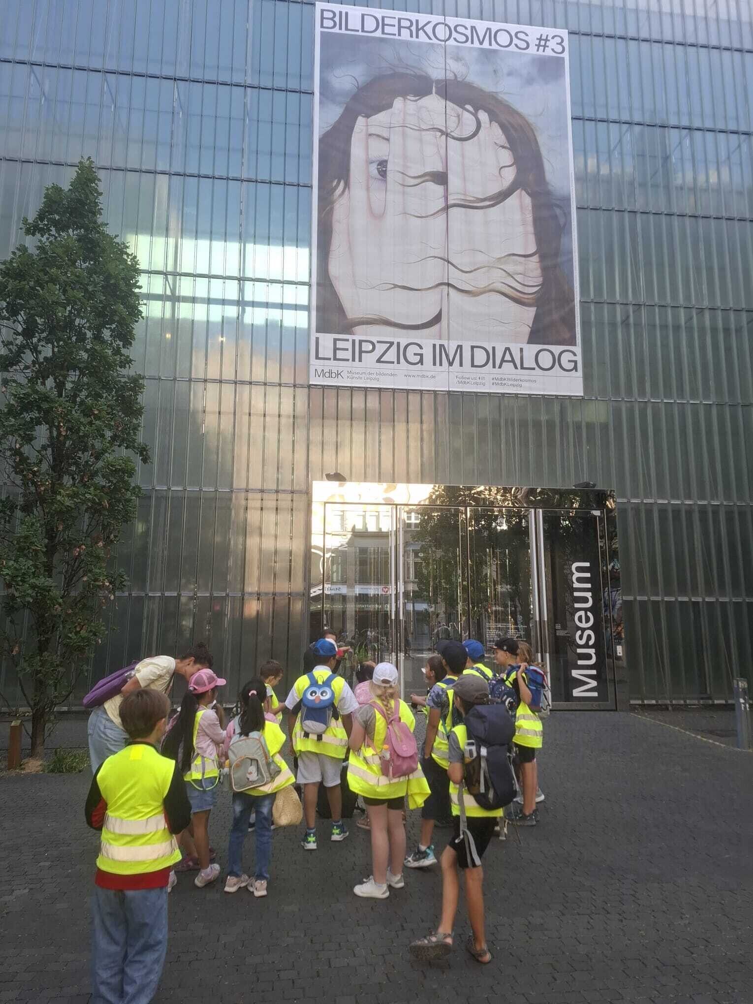 Kinder in gelben Warnwesten stehen vor dem gro&szlig;en Eingang zum Museum der bildenden K&uuml;nste