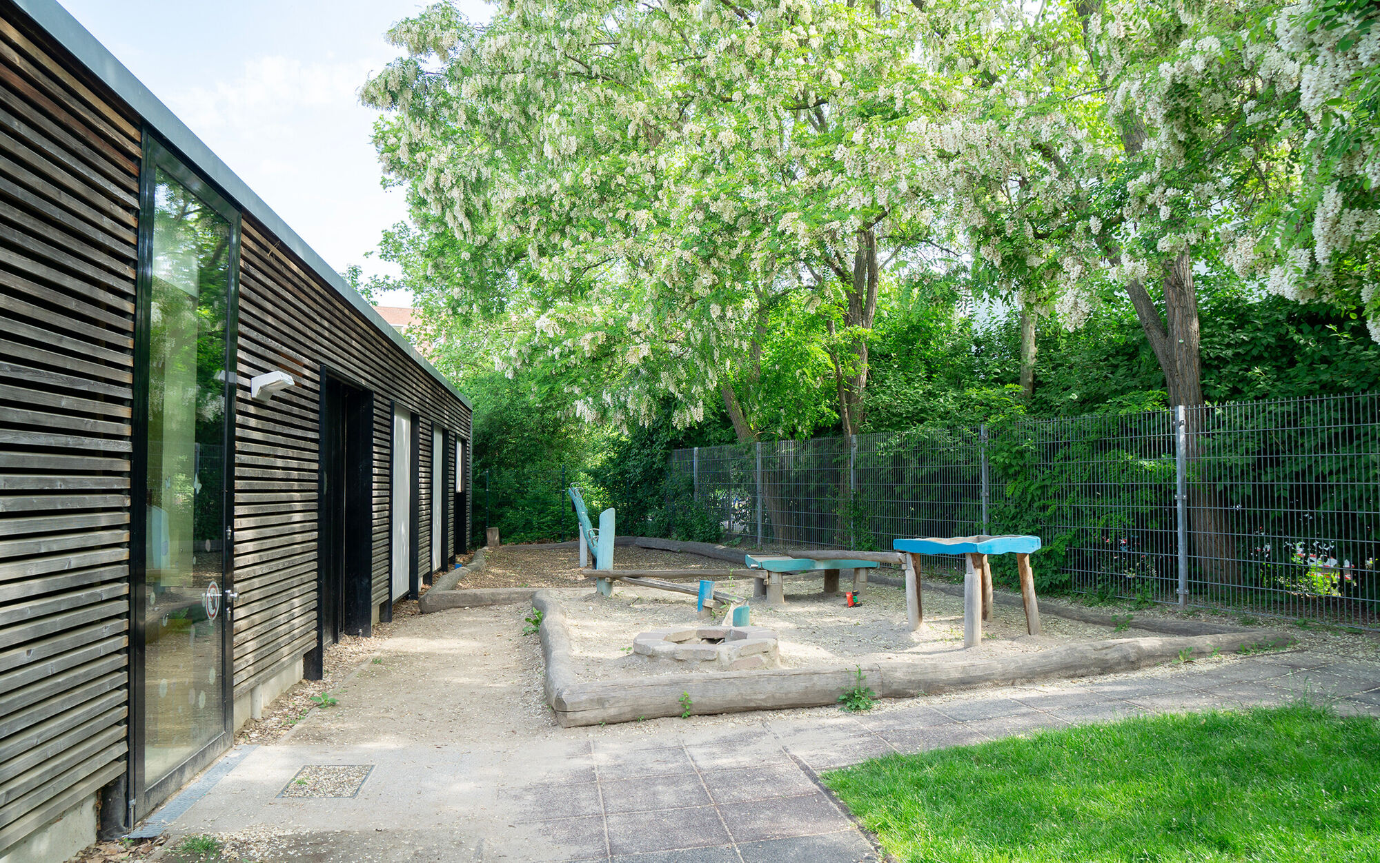 ein Sandkasten mit Wasserstrecke und einer Wippe im Hintergrund