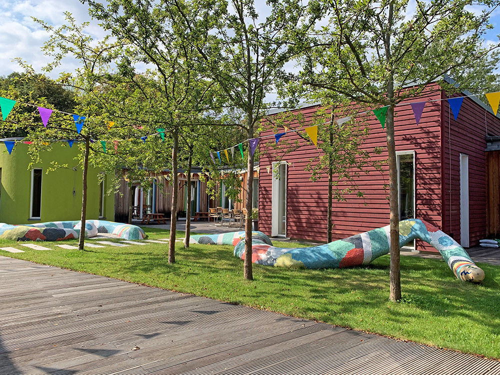 Ein kleinerer Innengarten mit Wiese, Bäumen und einer bunten Schlangenskulptur.