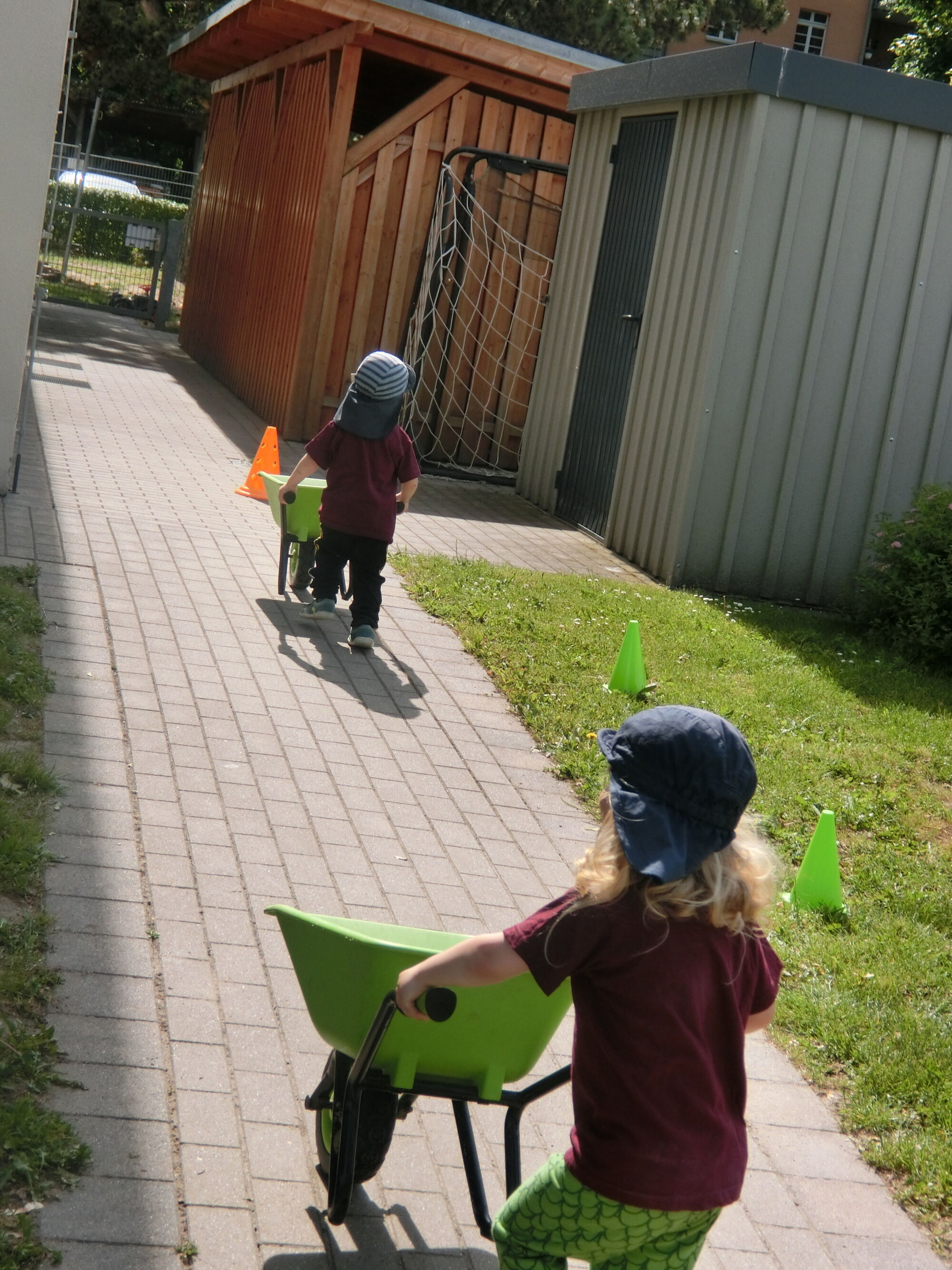 Kinder absolvieren einen Parcours mit einer kleinen Schubkarre