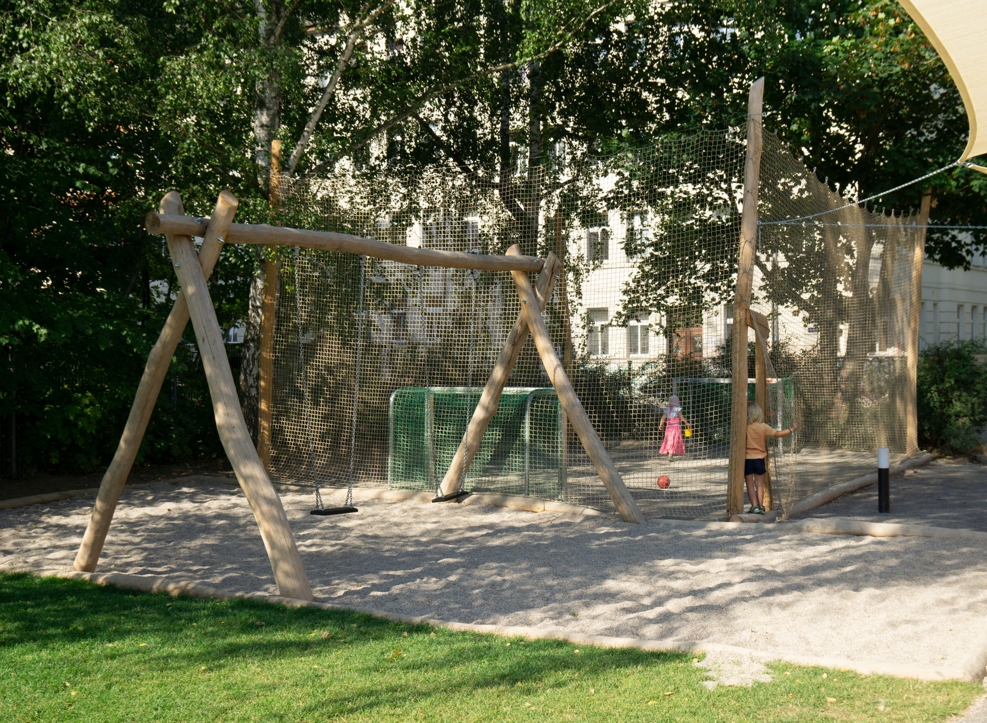 Zwei große Schaukeln neben einem Fussballplatz