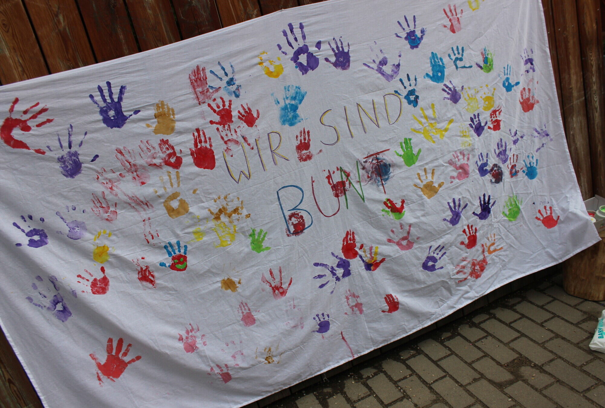Ein selbstgestalteter Banner mit bunten H&auml;nden und der Aufschrift "Wir sind bunt"