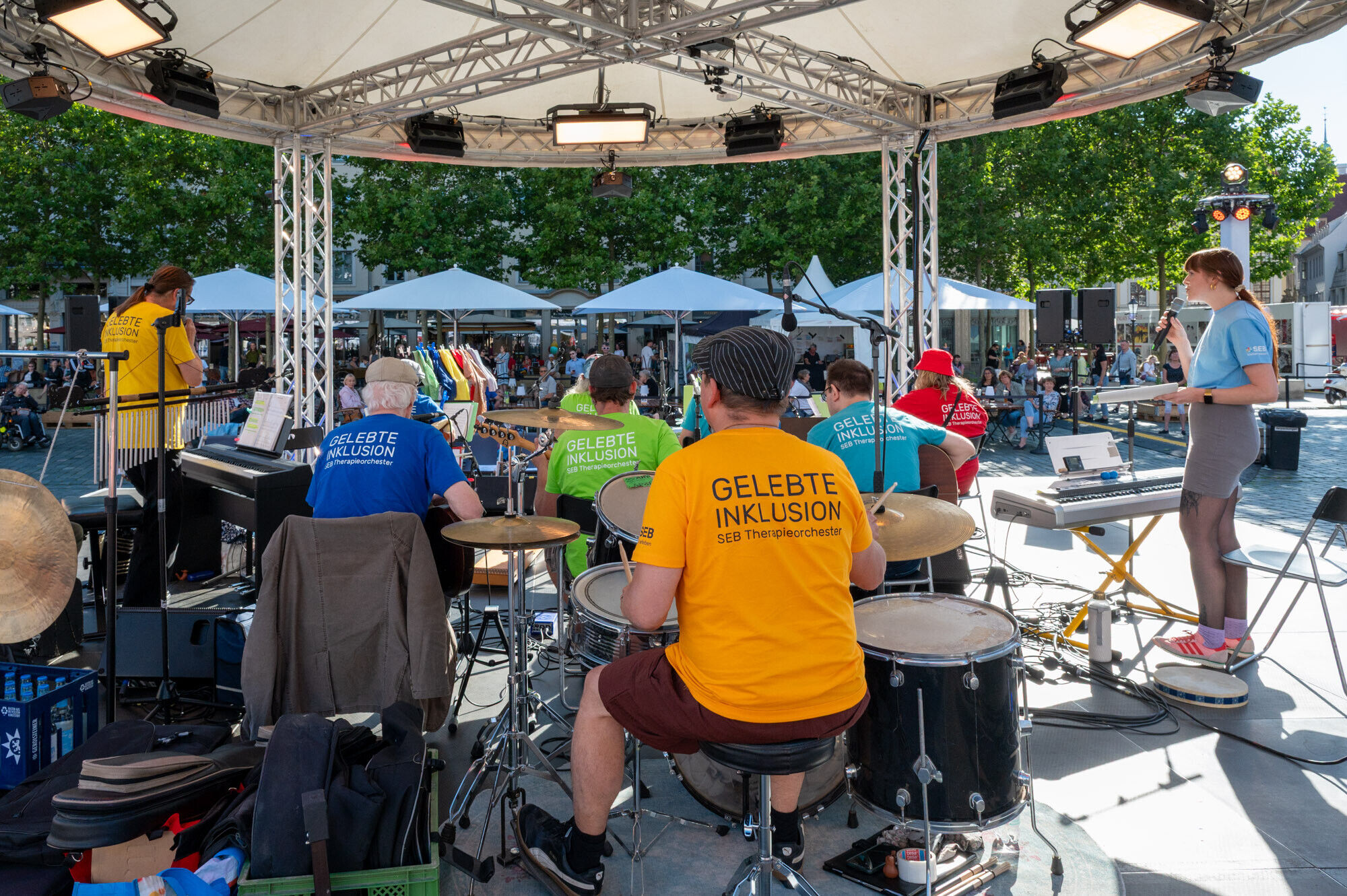 Alle auf der B&uuml;hne tragen bunte T-Shirts mit der Aufschrift "Gelebte Inklusion"