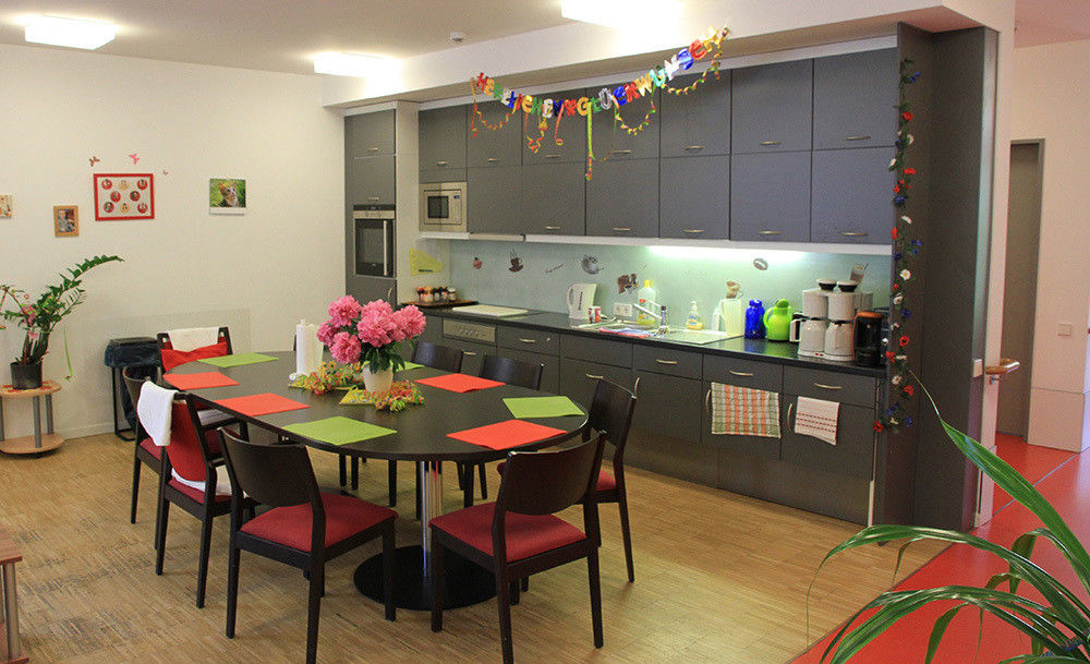 Ein Gemeinschaftsraum mit Küchenzeile, Tisch und Stühlen.