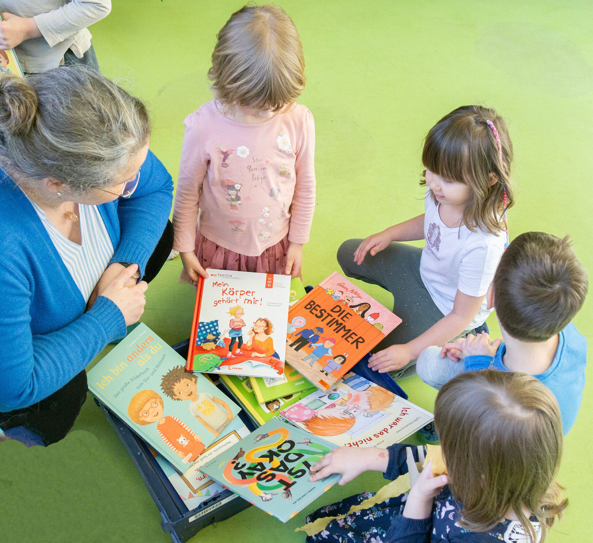Kinder sitzenauf dem Boden und schauen sich B&uuml;cher an