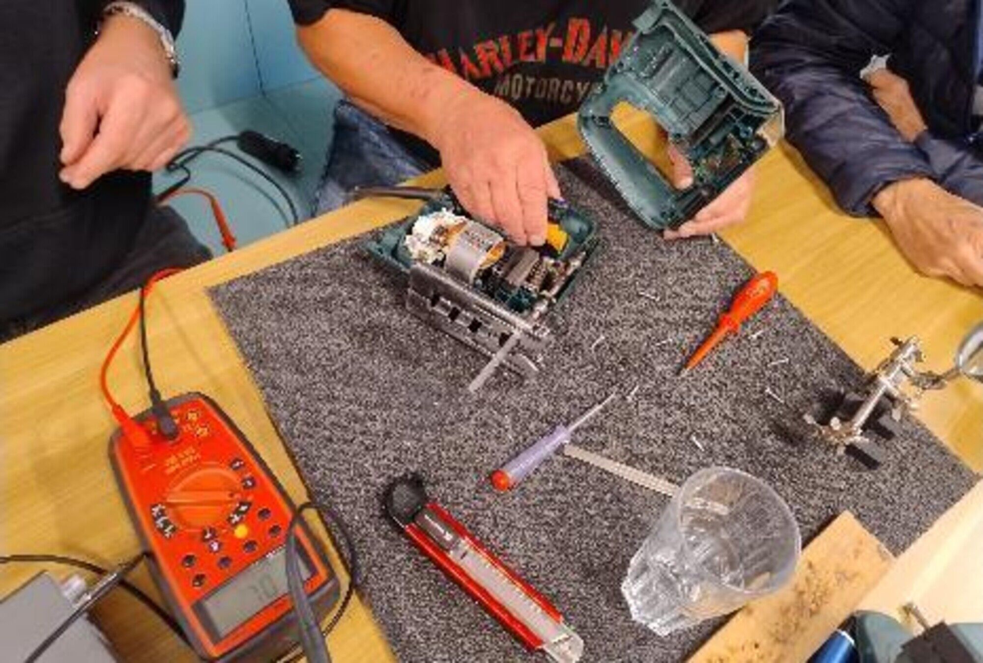 Werkzeuge und Ger&auml;te liegen auf einem Tisch. H&auml;nde sind zu sehen.