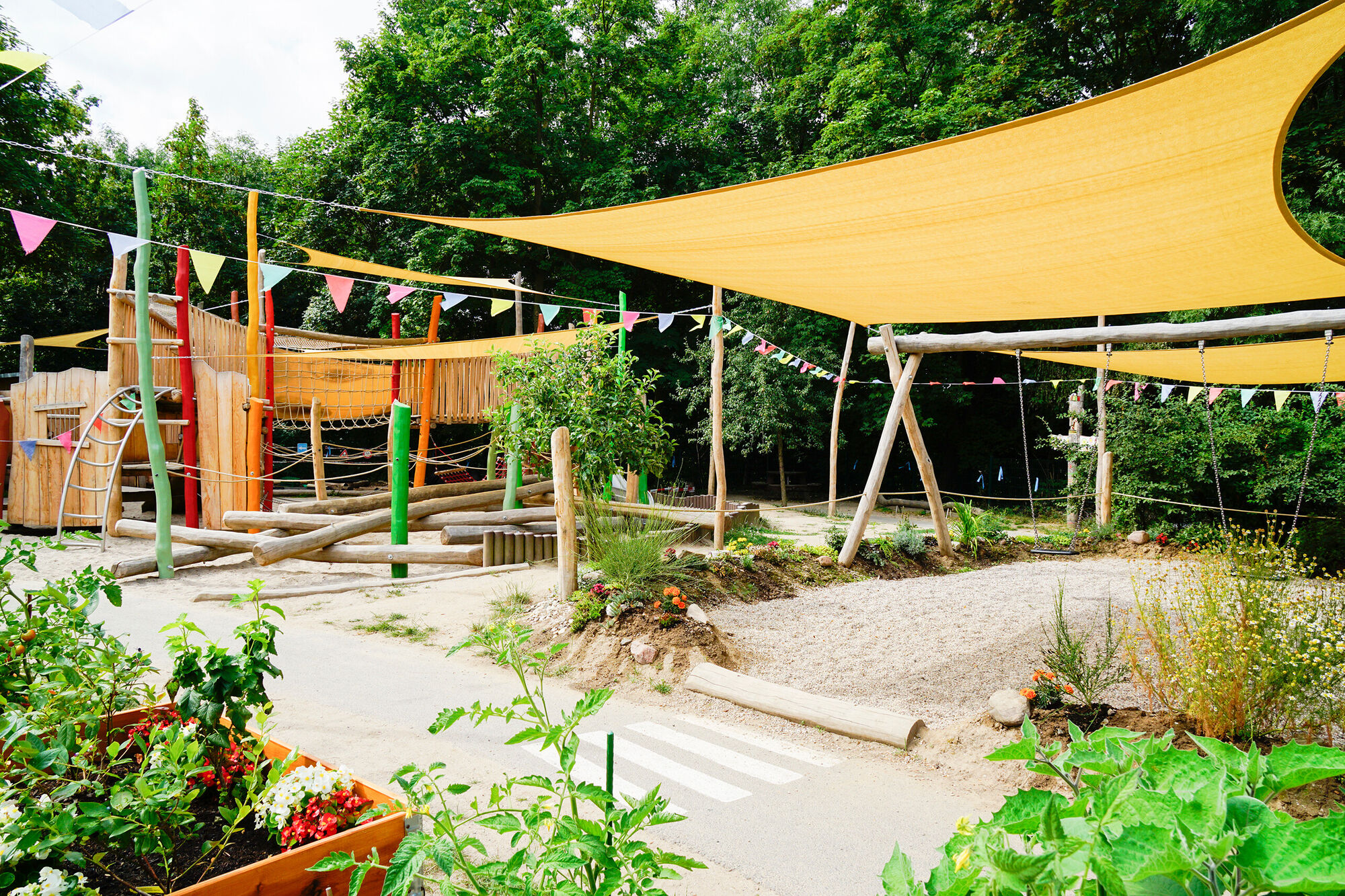 Der Garten mit Bereichen zum Klettern, schaukeln, Rollerfahren und Gemüse anpflanzen.