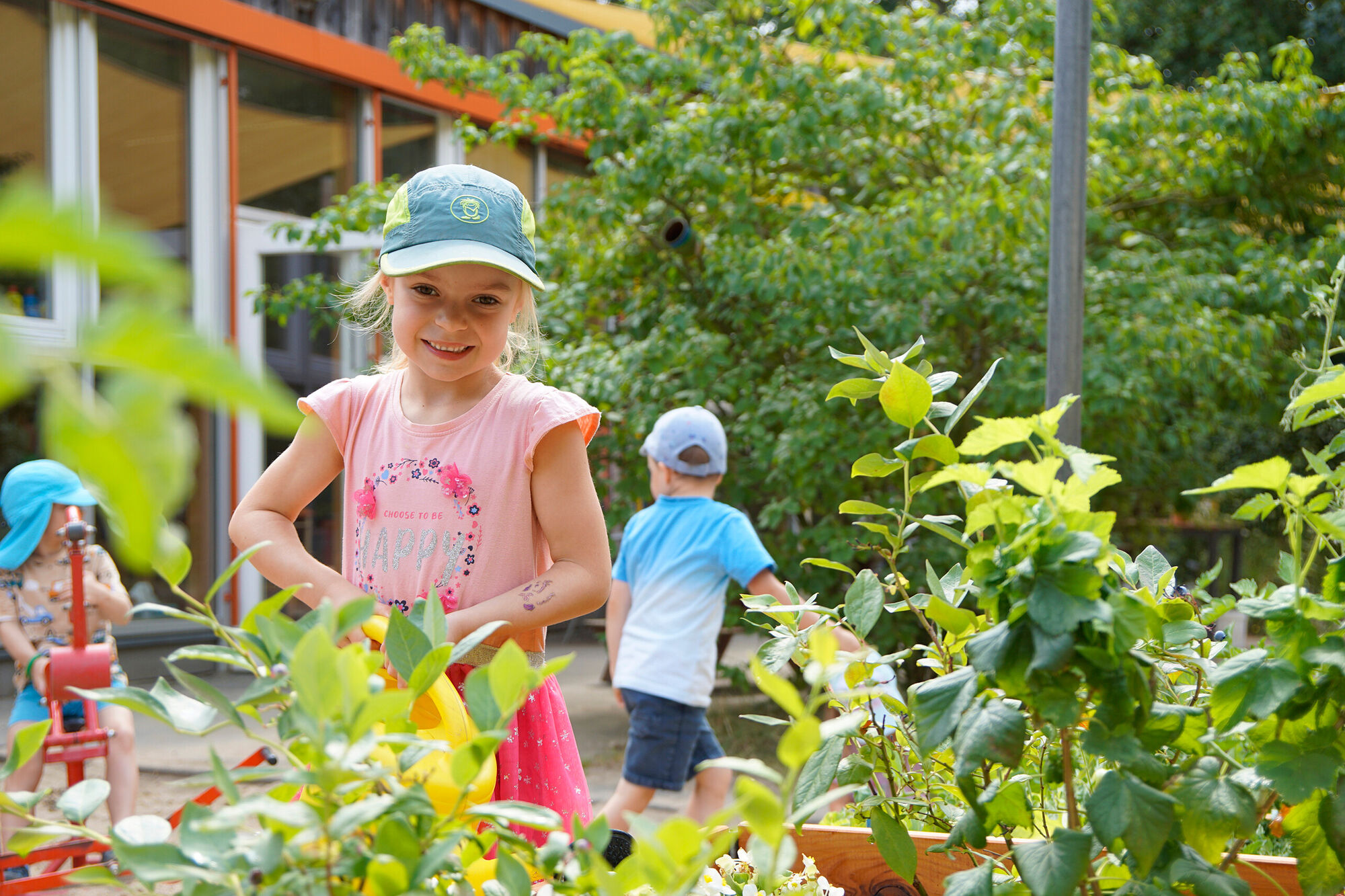 Ein Kinde gießt Pflanzen in einem Hochbeet.