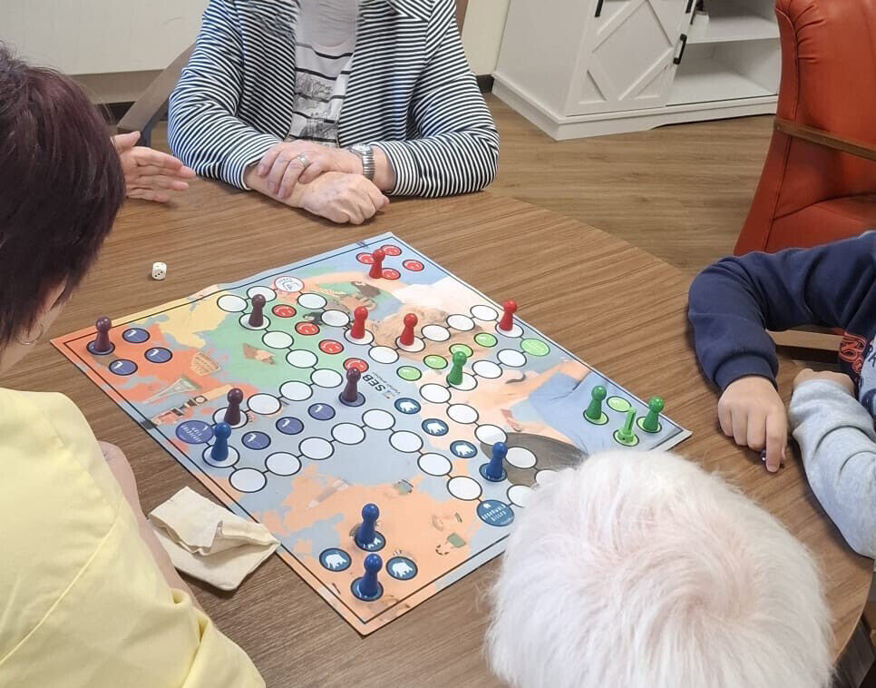Ein Mensch &auml;rger dich nicht Spiel auf einem Tisch. Drumherum sitzen Kinder und &auml;ltere Menschen