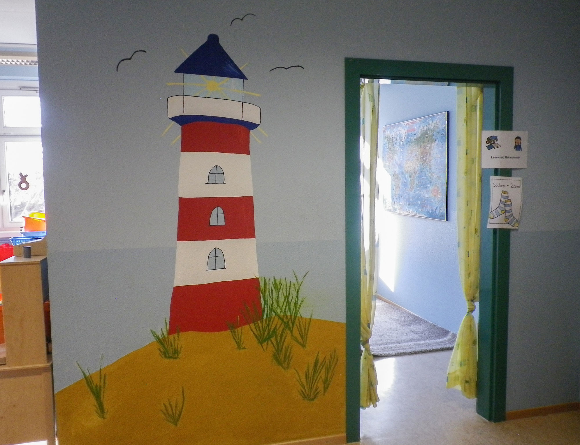 Ein Leuchtturm mit Dünen ist an eine Wand gemalt.