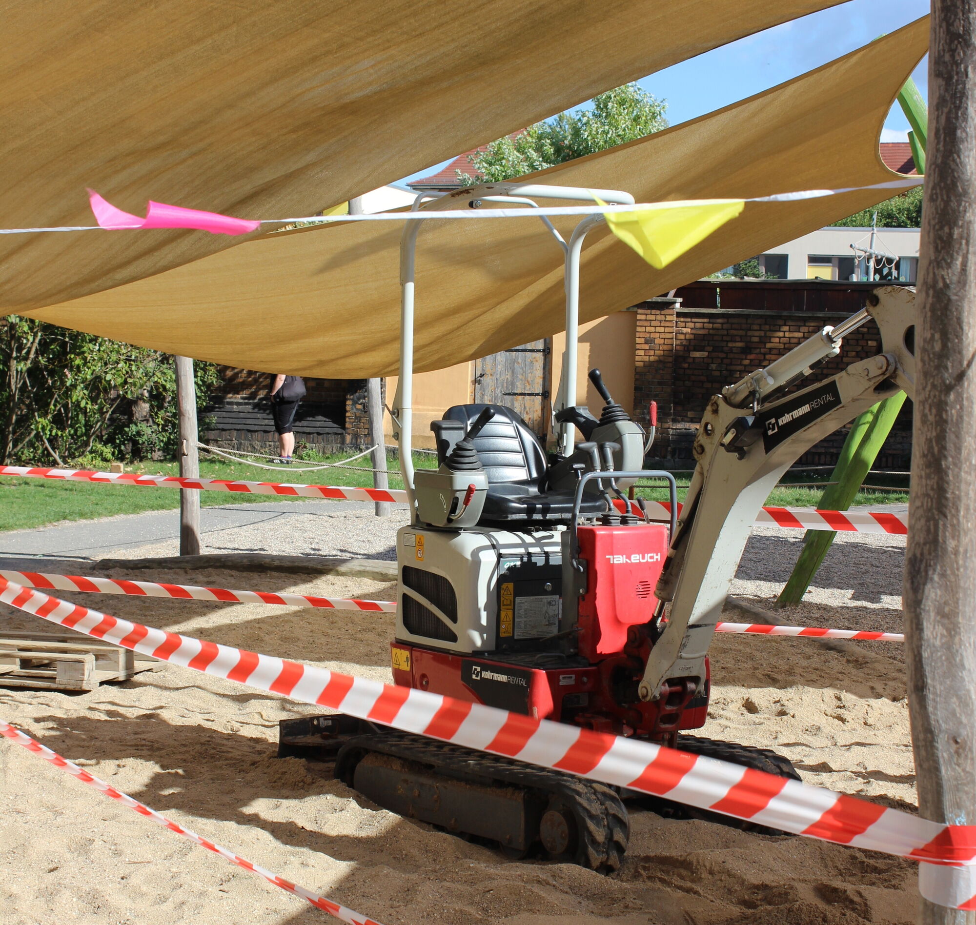 ein elektrischer gro&szlig;er Bagger steht im Sandkasten