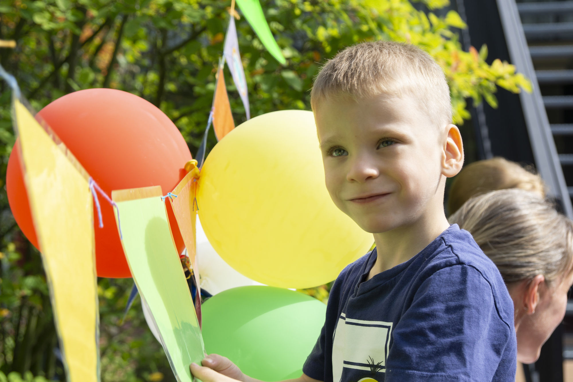 Ein Junge steht vor einer bunten Girlande mit Luftballons