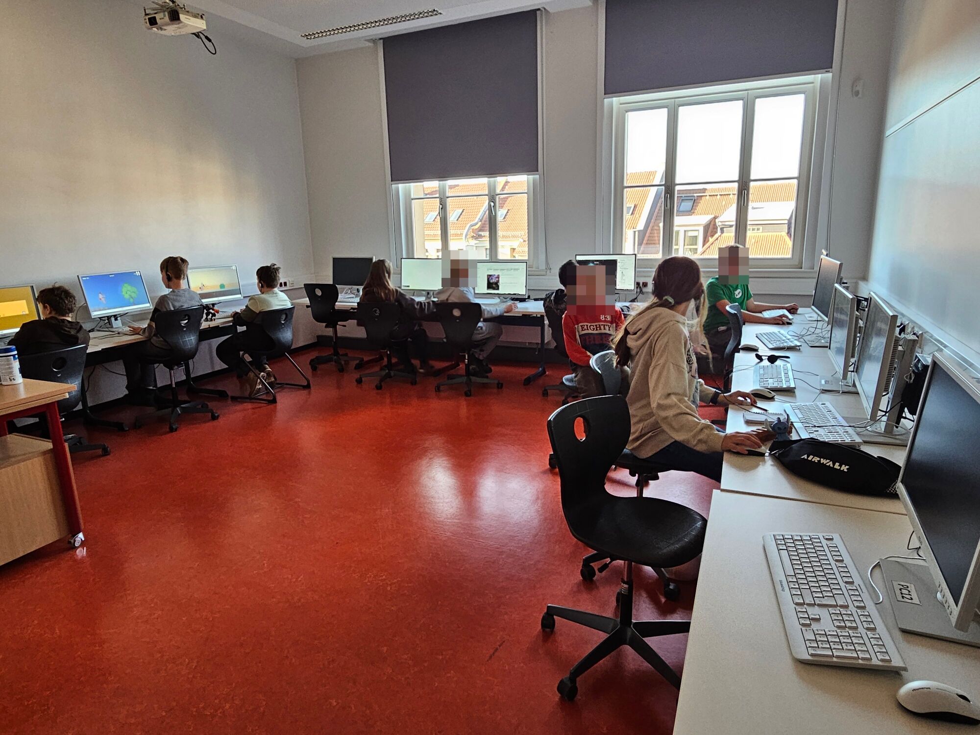 Kinder sitzen an Tischen mit Computern