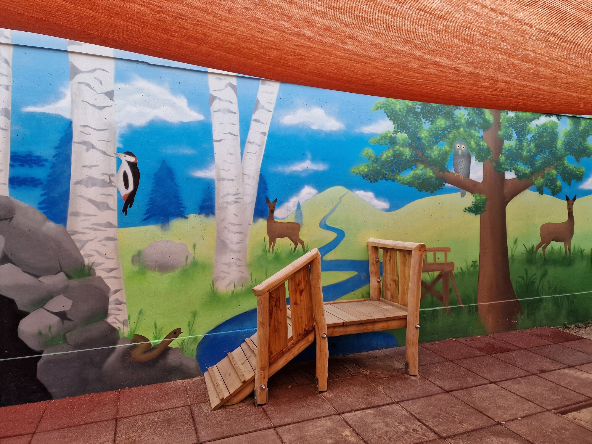 ein Podest aus Holz an einer Wand mit Waldmotiv