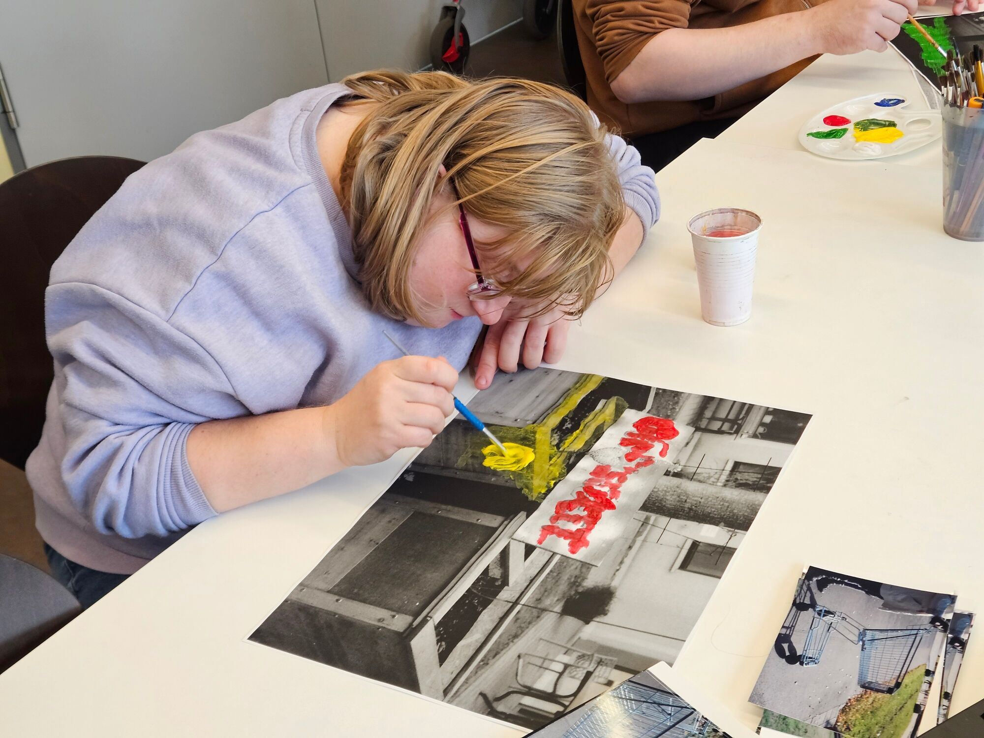 Eine Frau malt mit gelber Farbe auf ein Foto