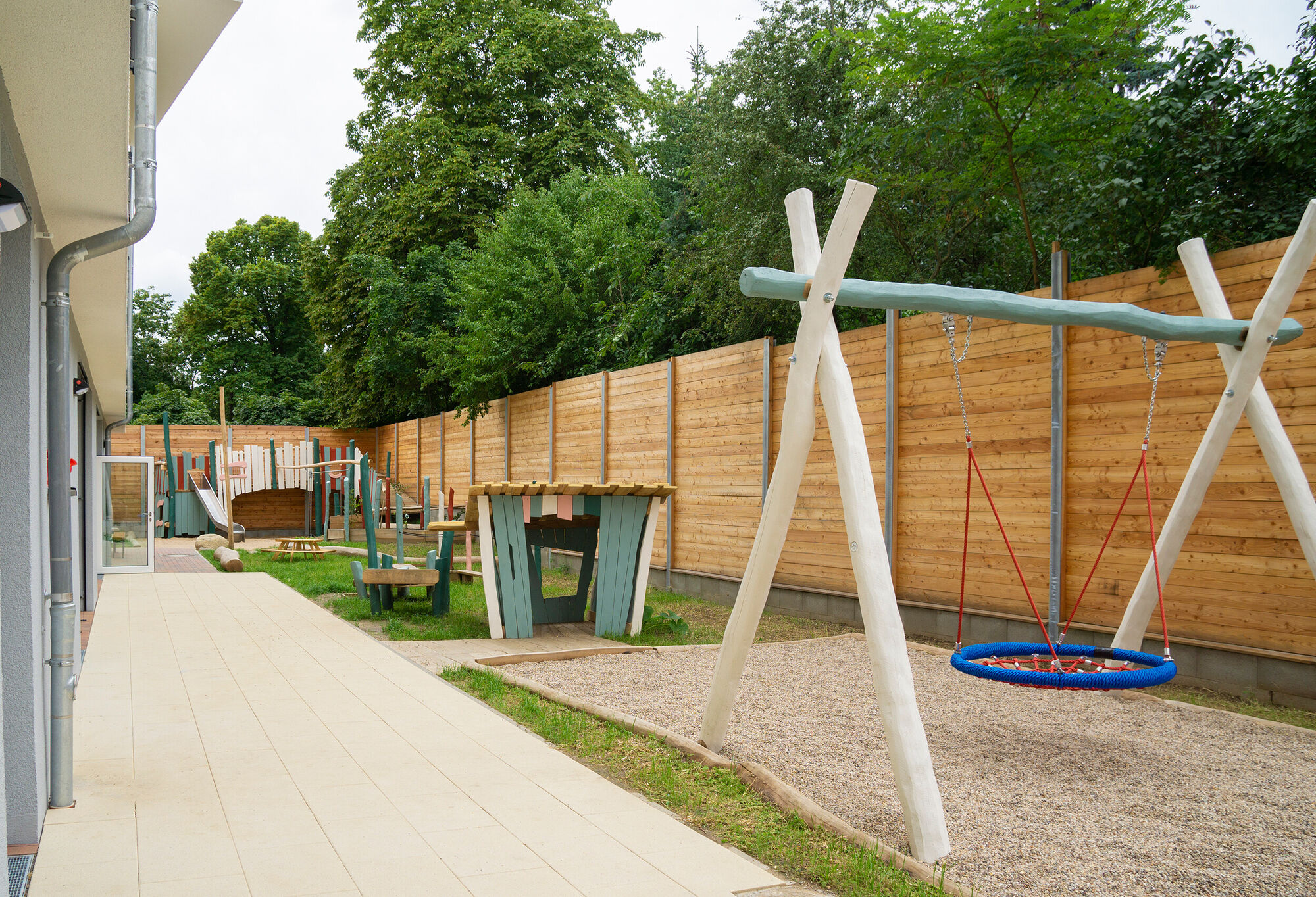 Eine nestschaukel mit Sandkasten, kleinen Spielhäuschen und Balancierstrecken.