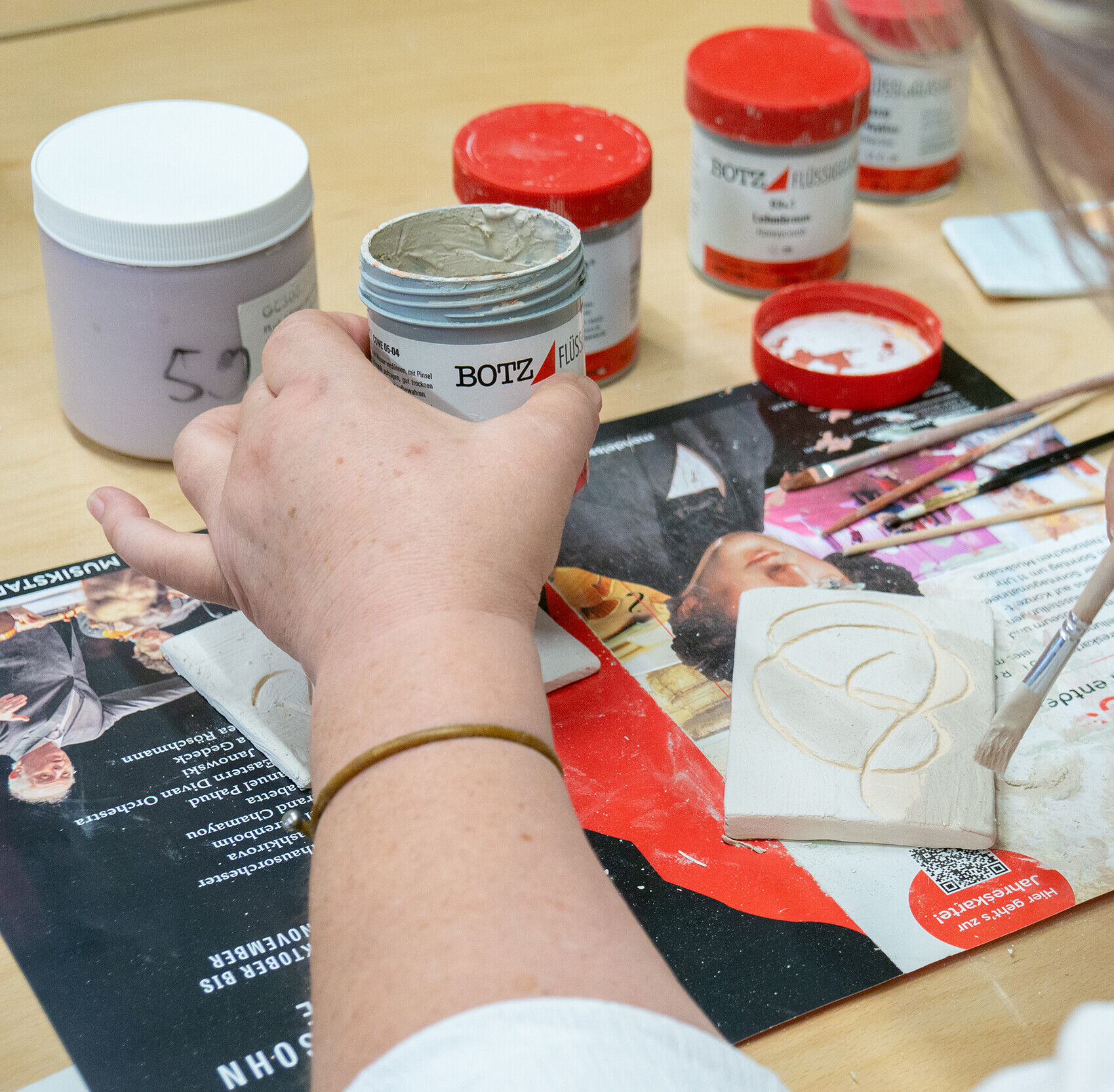 Eine Frau bemalt ein Tonstück.