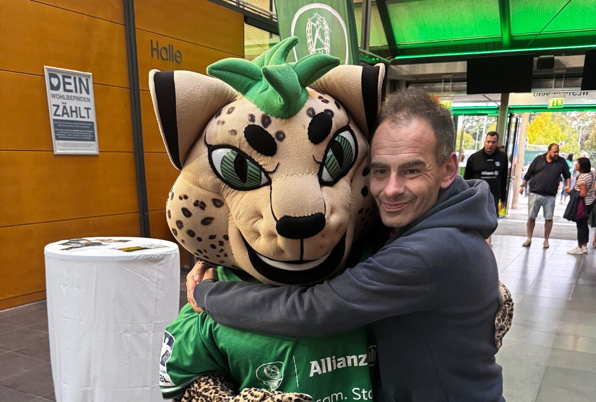 Ein Mann umarmt das lebensgroße Maskottchen, einen Leoparden