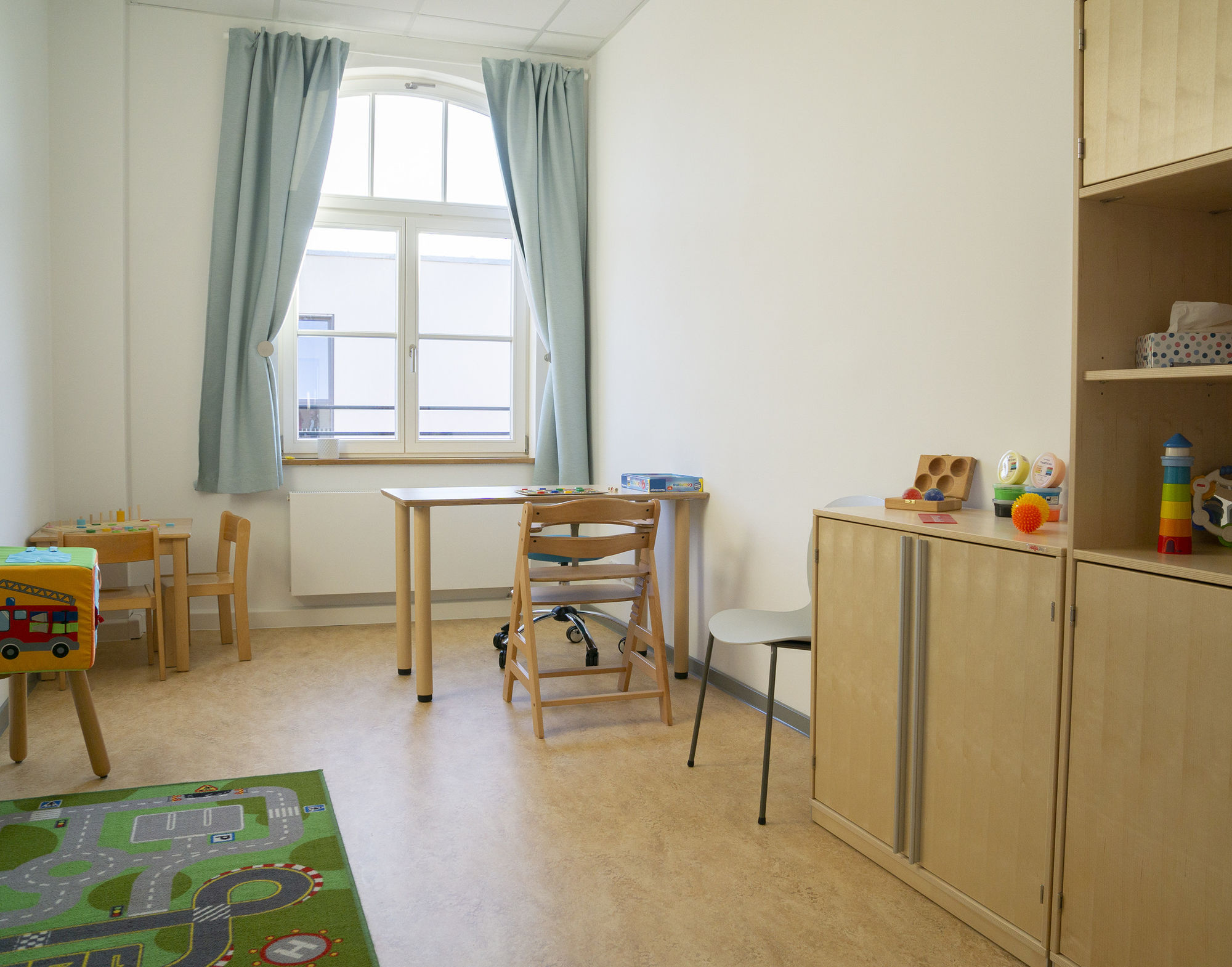 ein Therapieraum mit Tischen, Stühlen, Spielen und weiteren Therapiematerialien