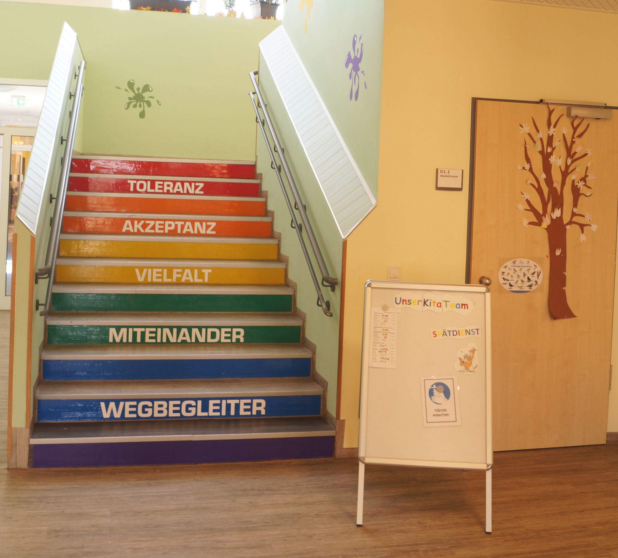 Eine bunte Treppe auf welcher die Worte Wegbegleiter, Miteinander, Vielfalt, Akzeptanz und Toleranz zu lesen sind.