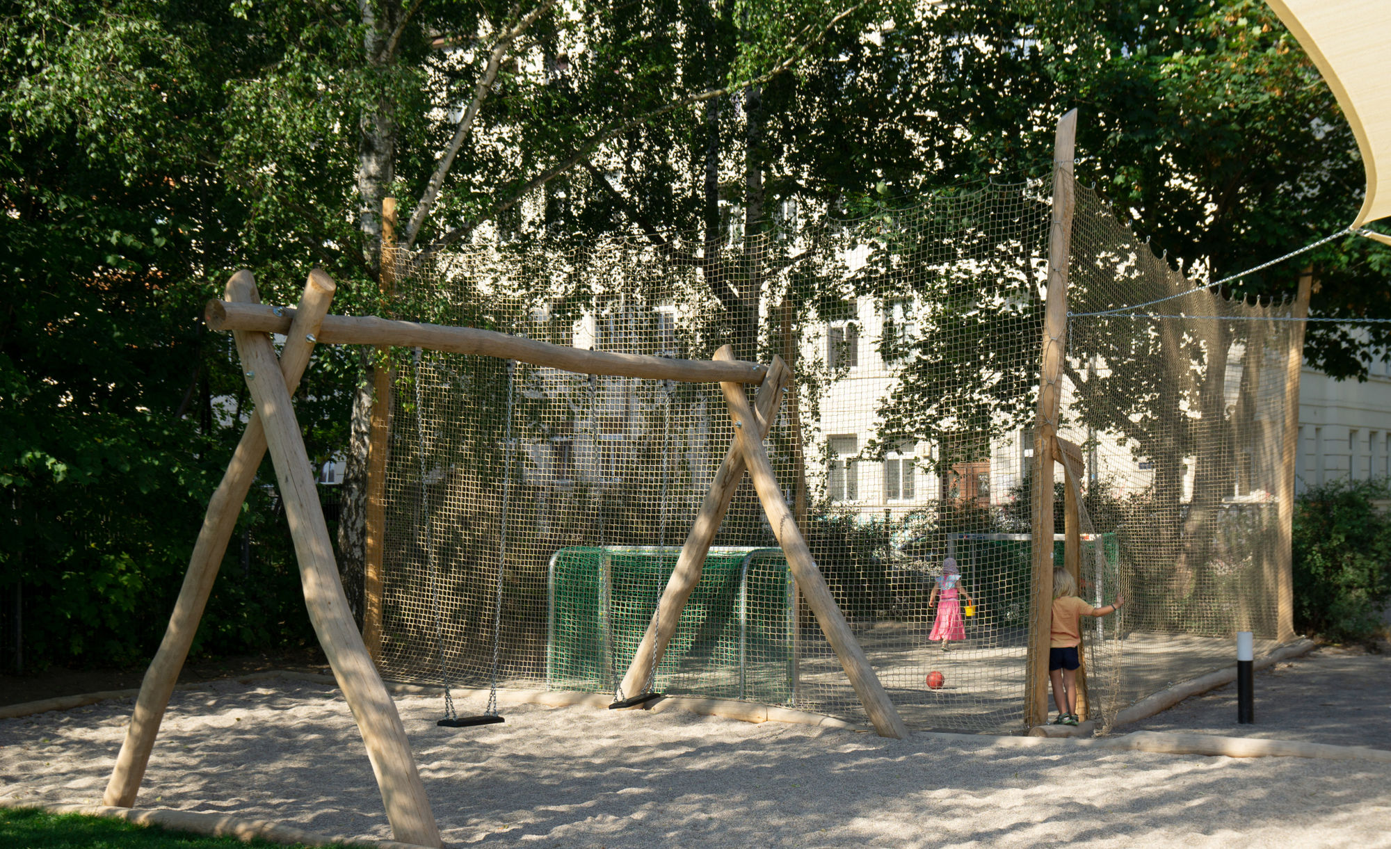 Zwei Schaukeln neben einem Fußballplatz.