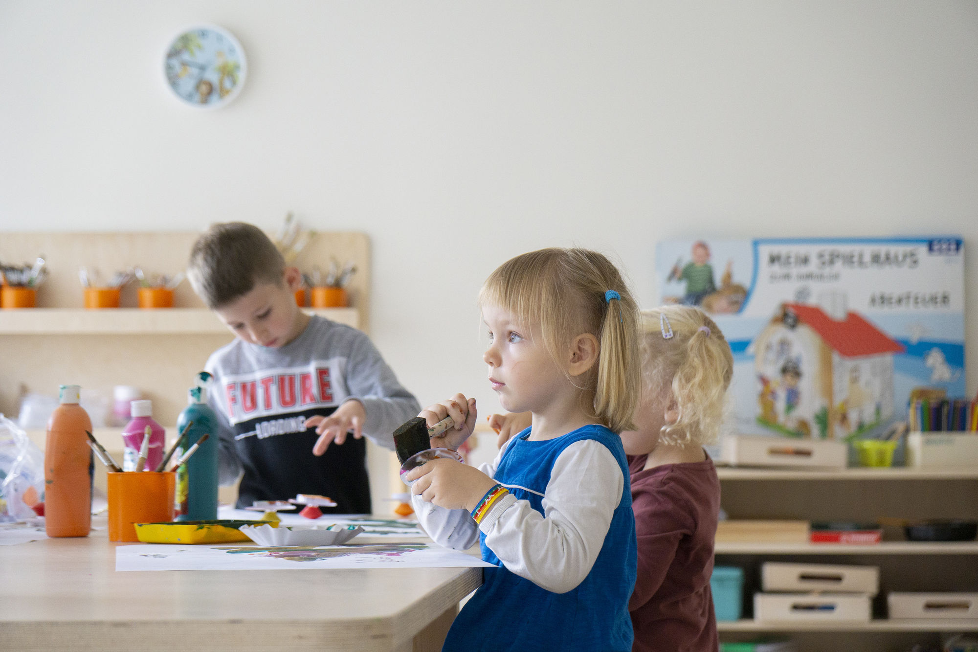 Kinder sitzen an einem Tisch mit Malfarben und zeichenblättern