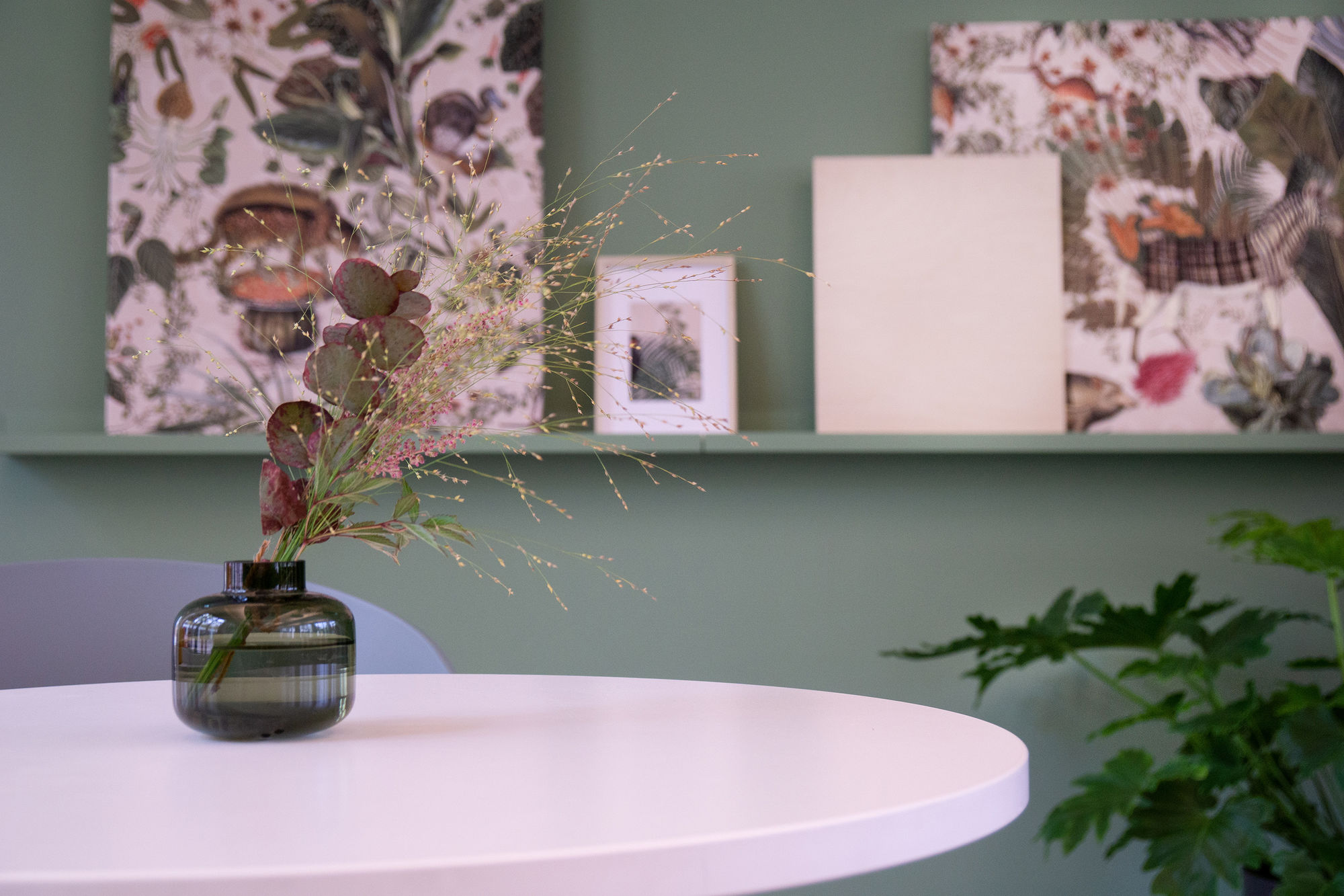 Eine Vase mit getrockneten Gräsern auf einem weißen runden Tisch