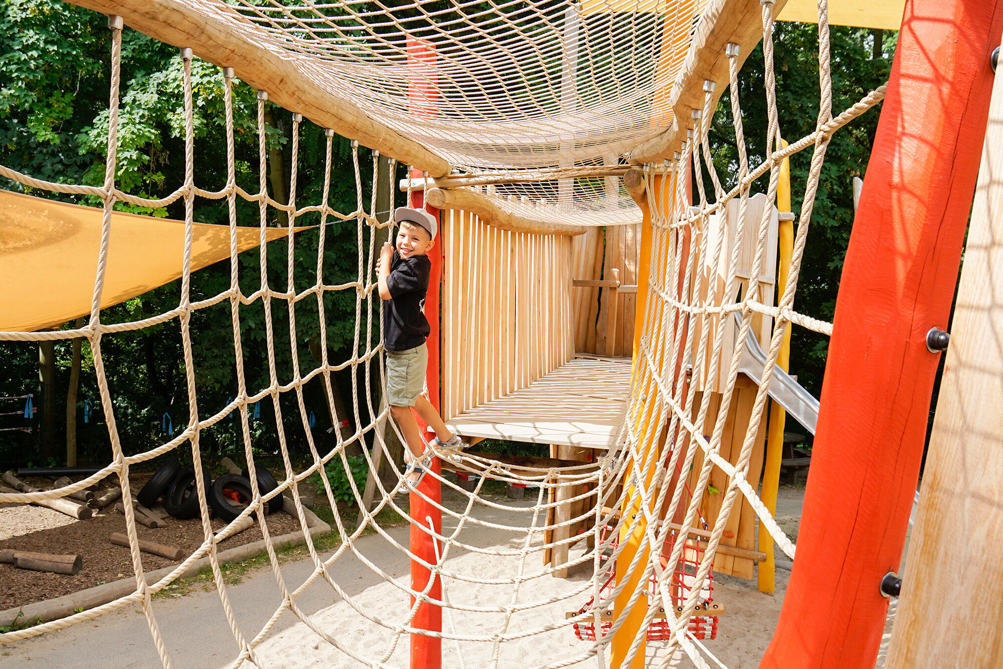 Ein Junge Klettert in einer Röhre aus Seilen.