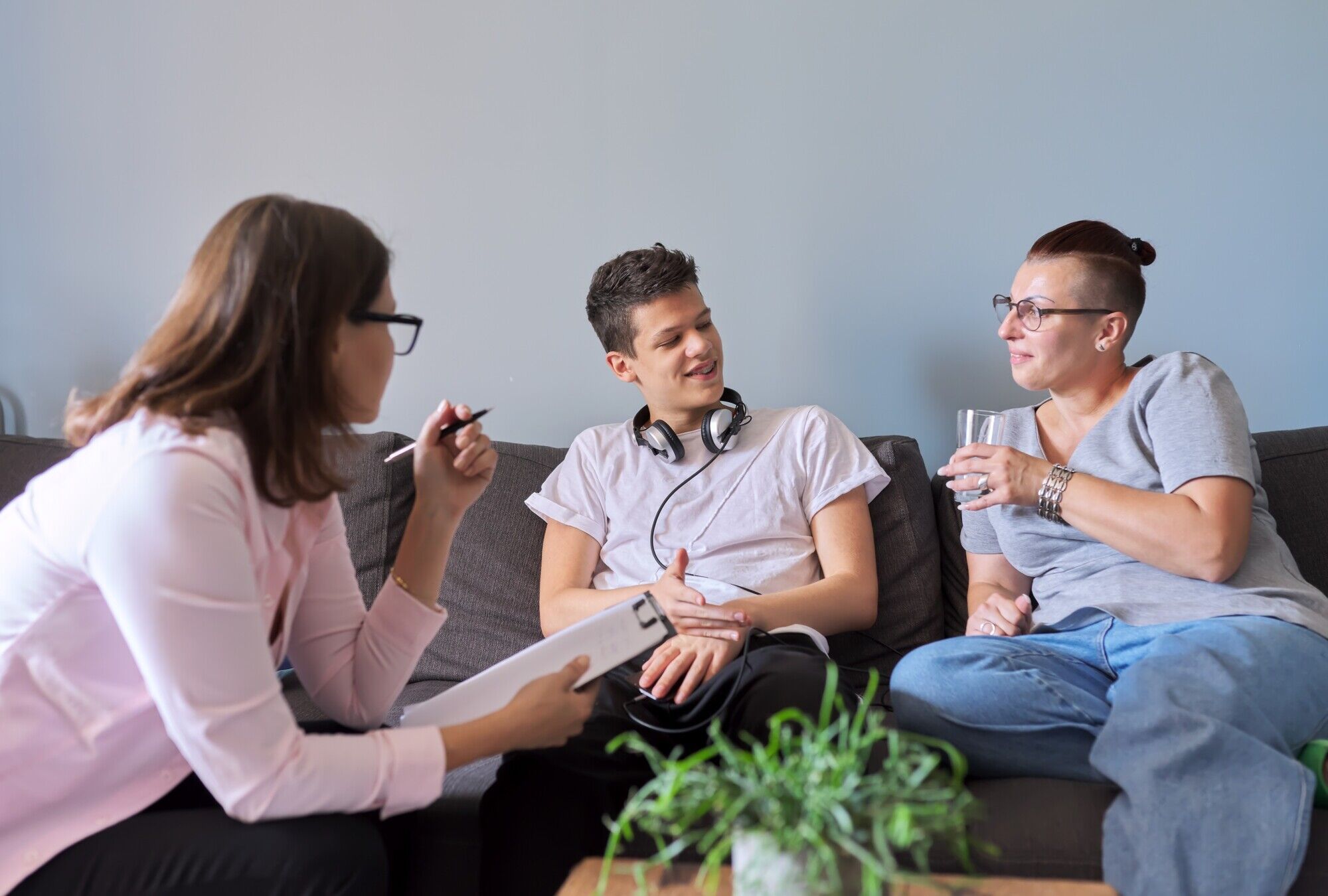 zwei Frauen in einem entspannten Gespr&auml;ch mit einem Jugendlichen sitzend auf einer Couch
