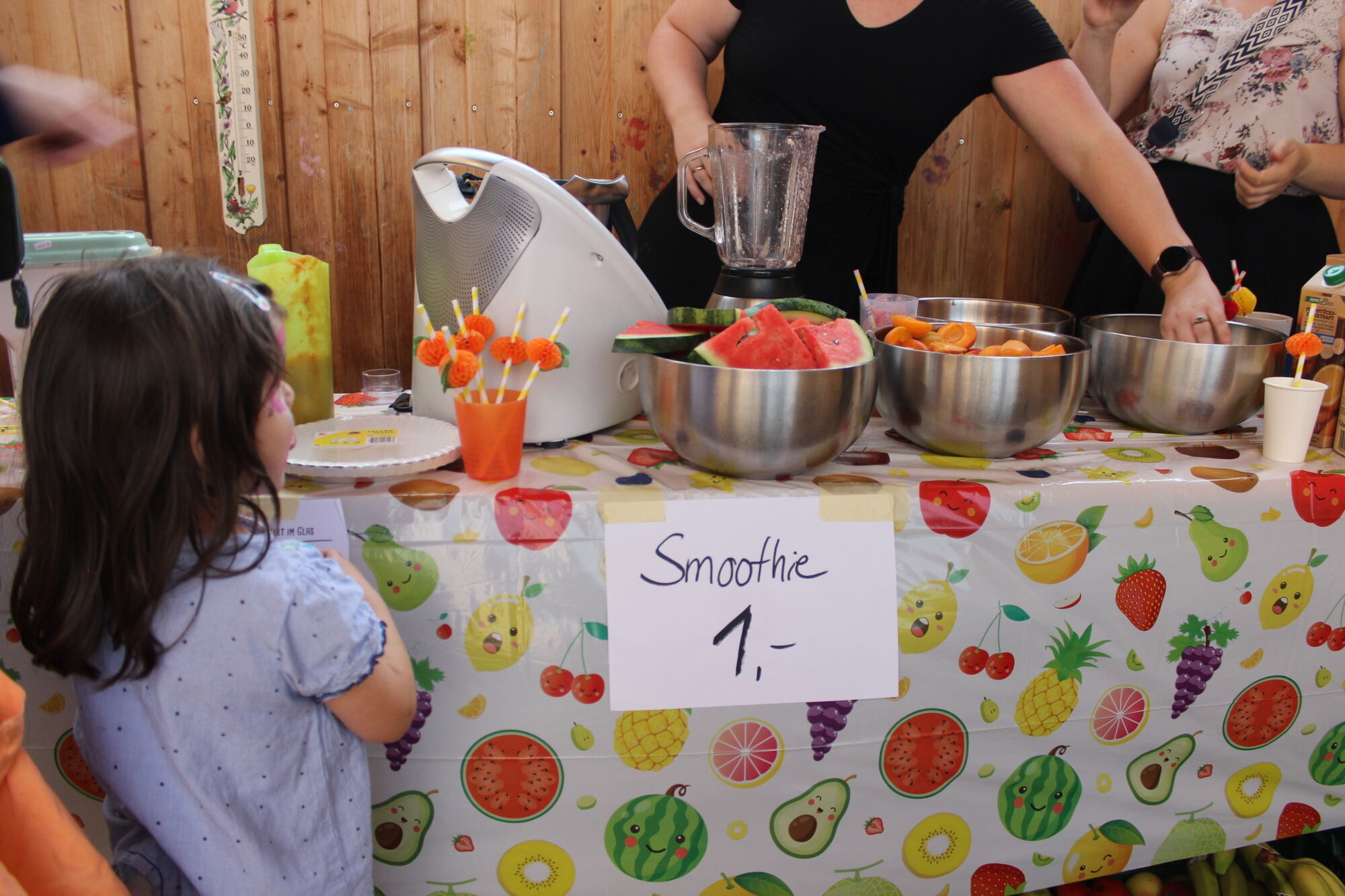 eine Smoothie-Station mit frischen Fr&uuml;chten, Mixer und bunten Bechern