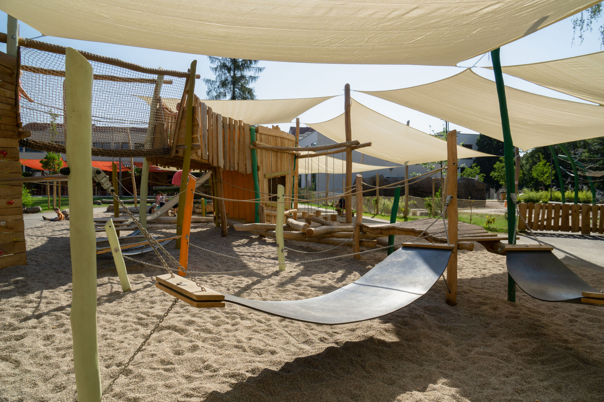 Ein großes Klettergerüst mit grünen Holzpfeilern und Netzen.