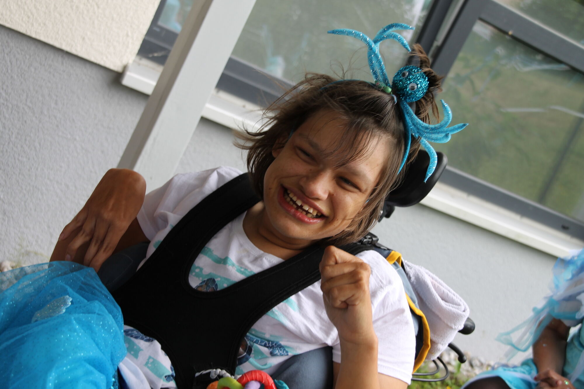 Eine lachende Frau im Rollstuhl mit einem Haarreifen mit Oktopus