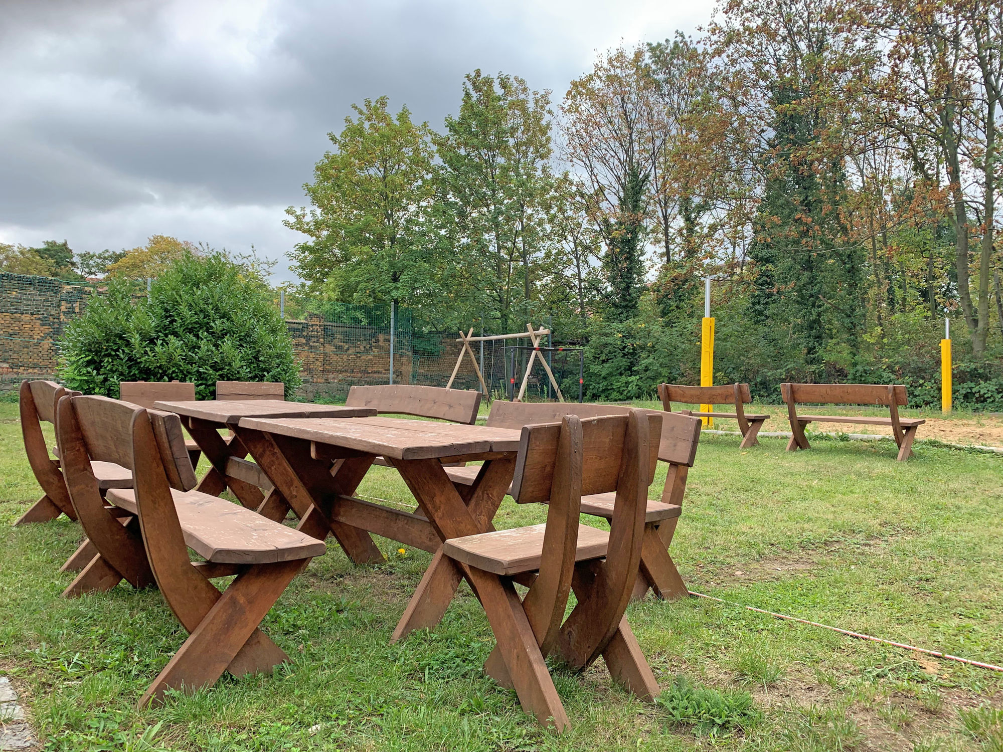 Eine Sitzgruppe im Garten mit Schaukeln und Wiese.