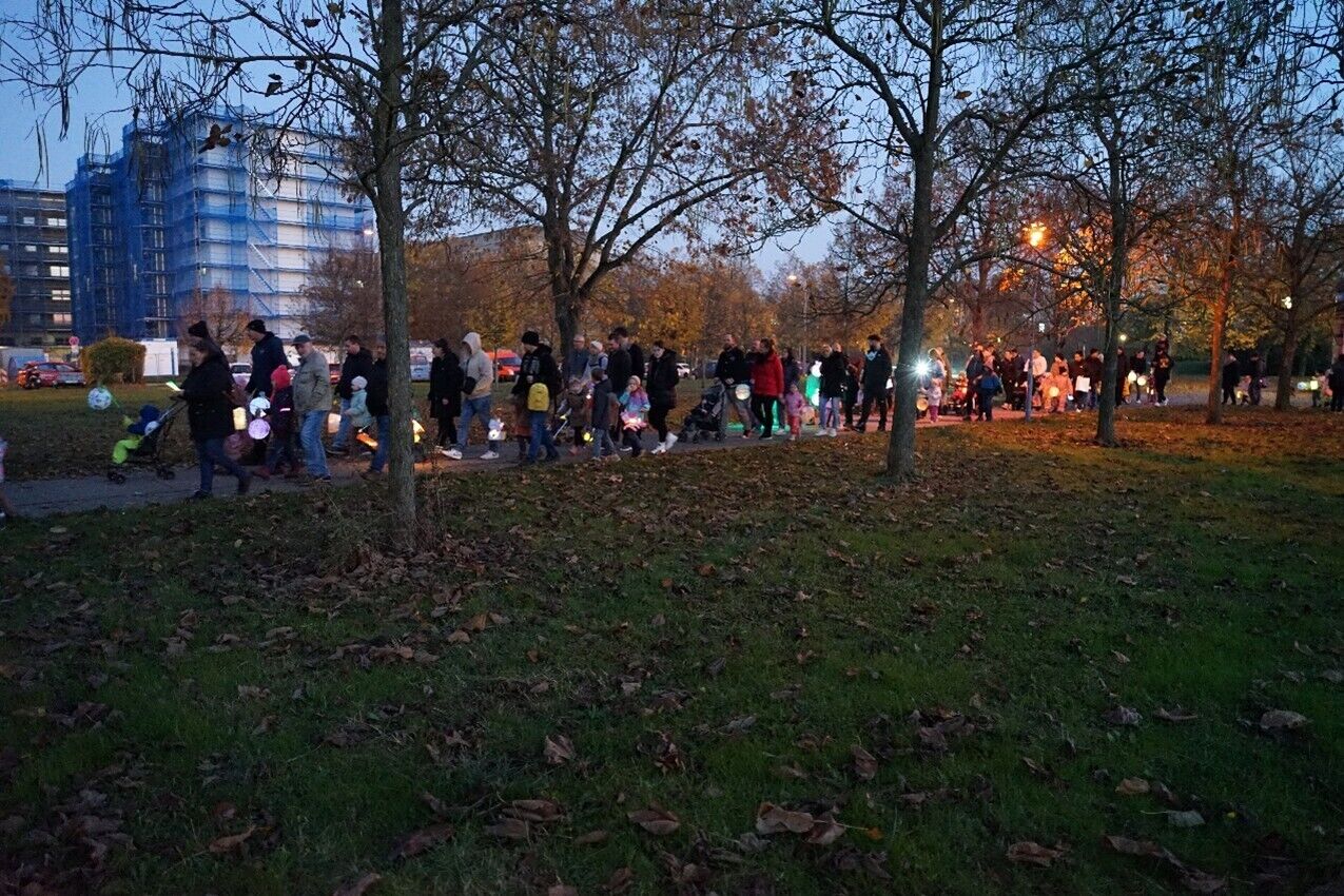 Viele Menschen laufen mit leuchtenden Laternen einen Weg entlang