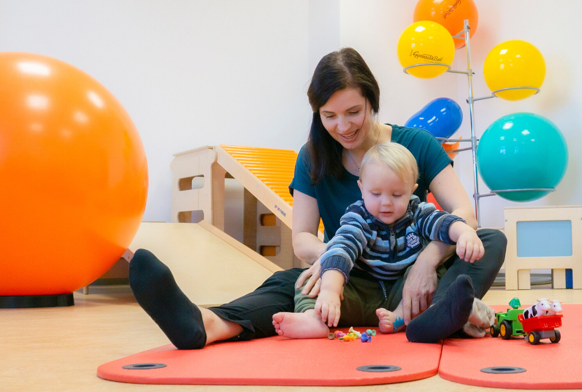 Frau und Kind sitzen auf Matte