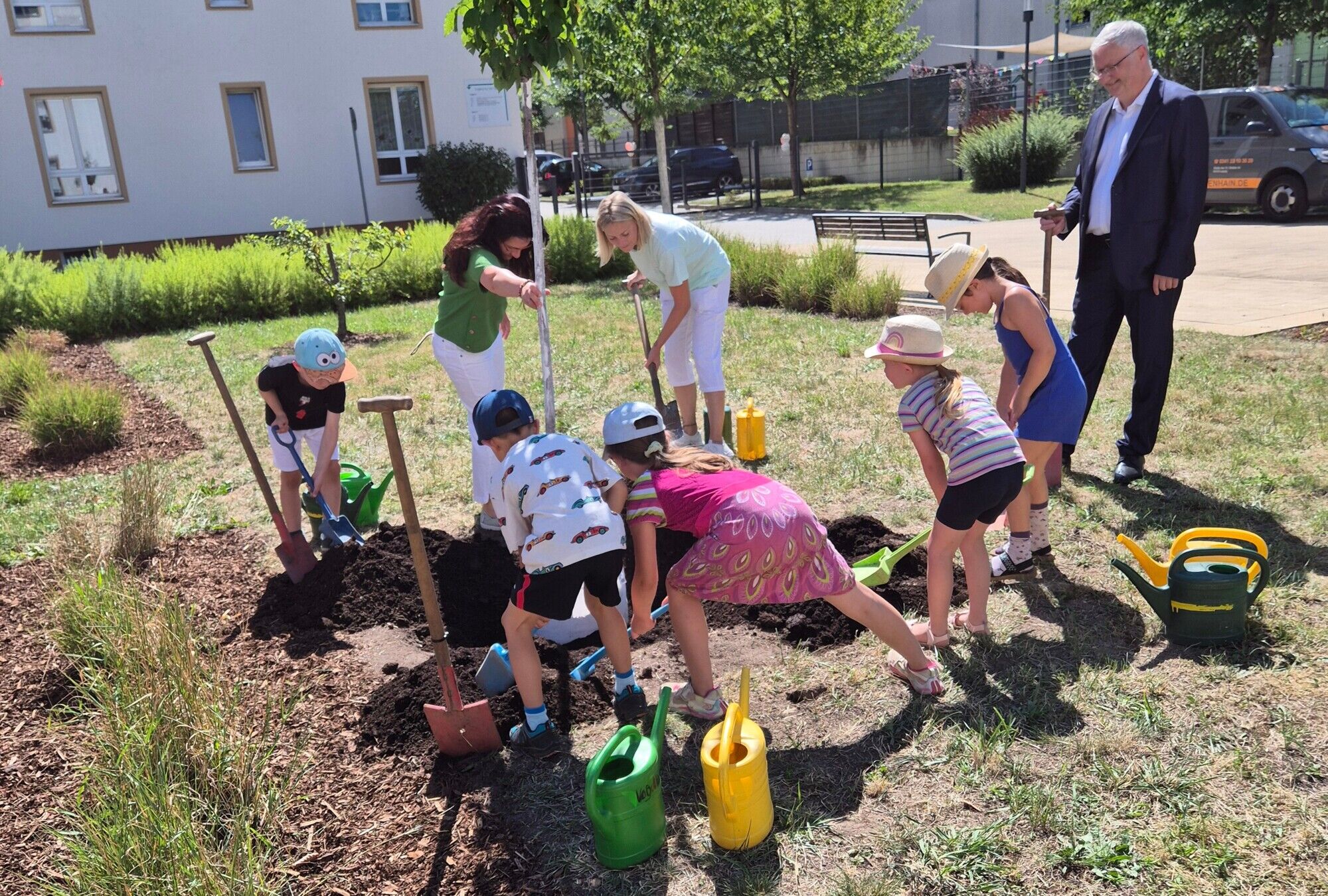 Kinder und Mitarbeiter*innen pflanzen einen Baum ein