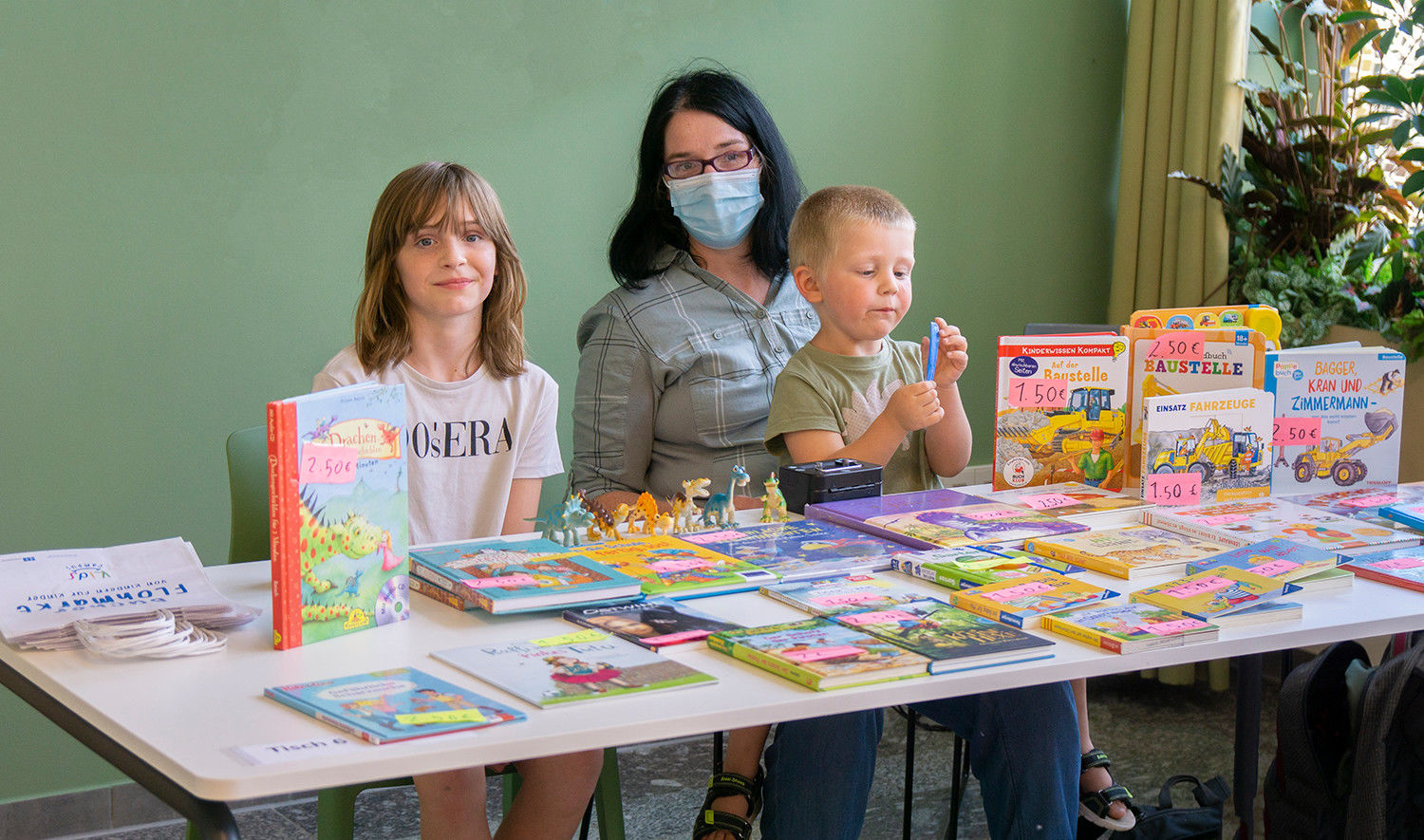 Eine Frau und zwei Kinder verkaufen Bücher