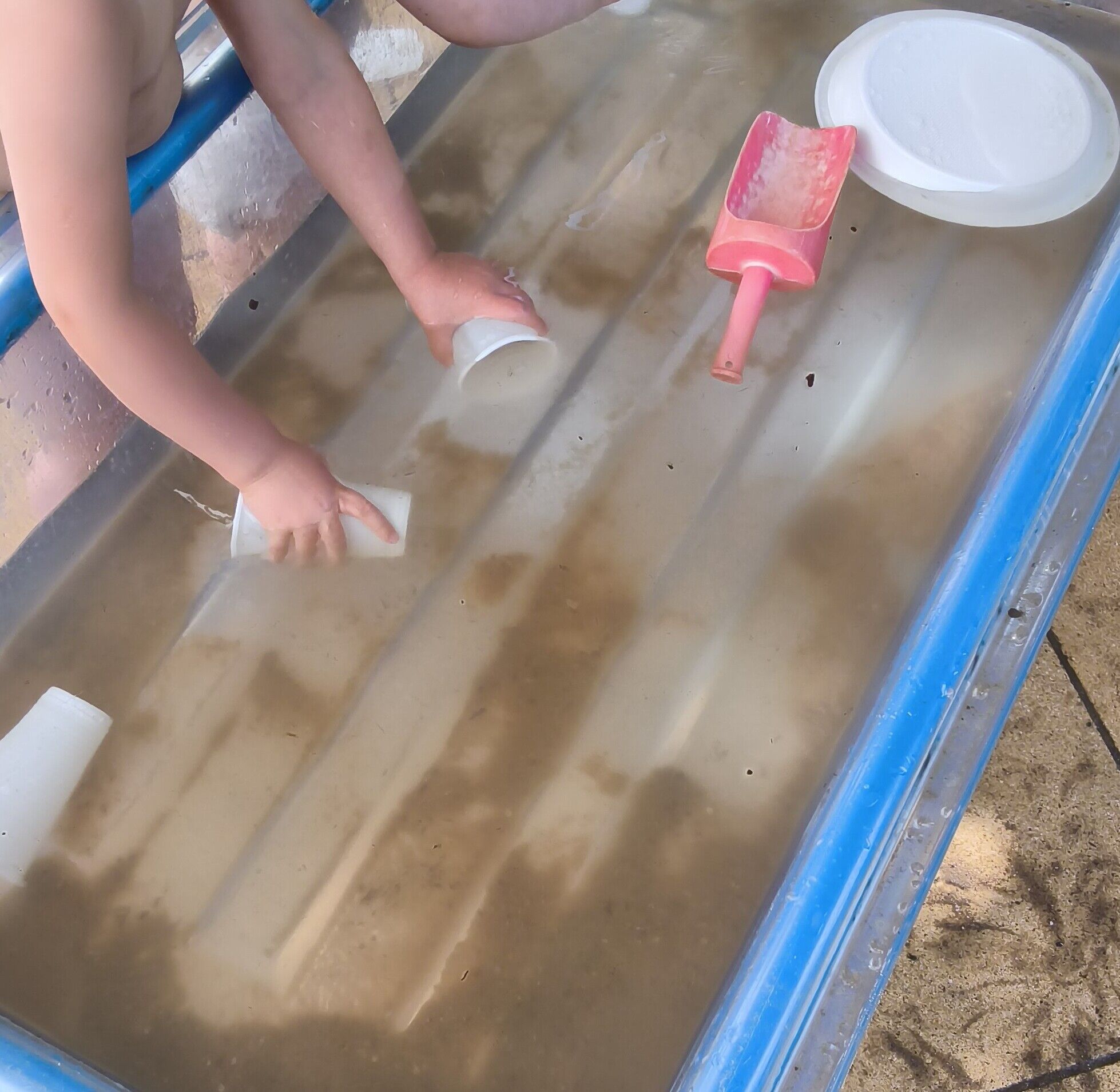 Kinderh&auml;nde mit Bechern in einem erh&ouml;hten Wasserbecken