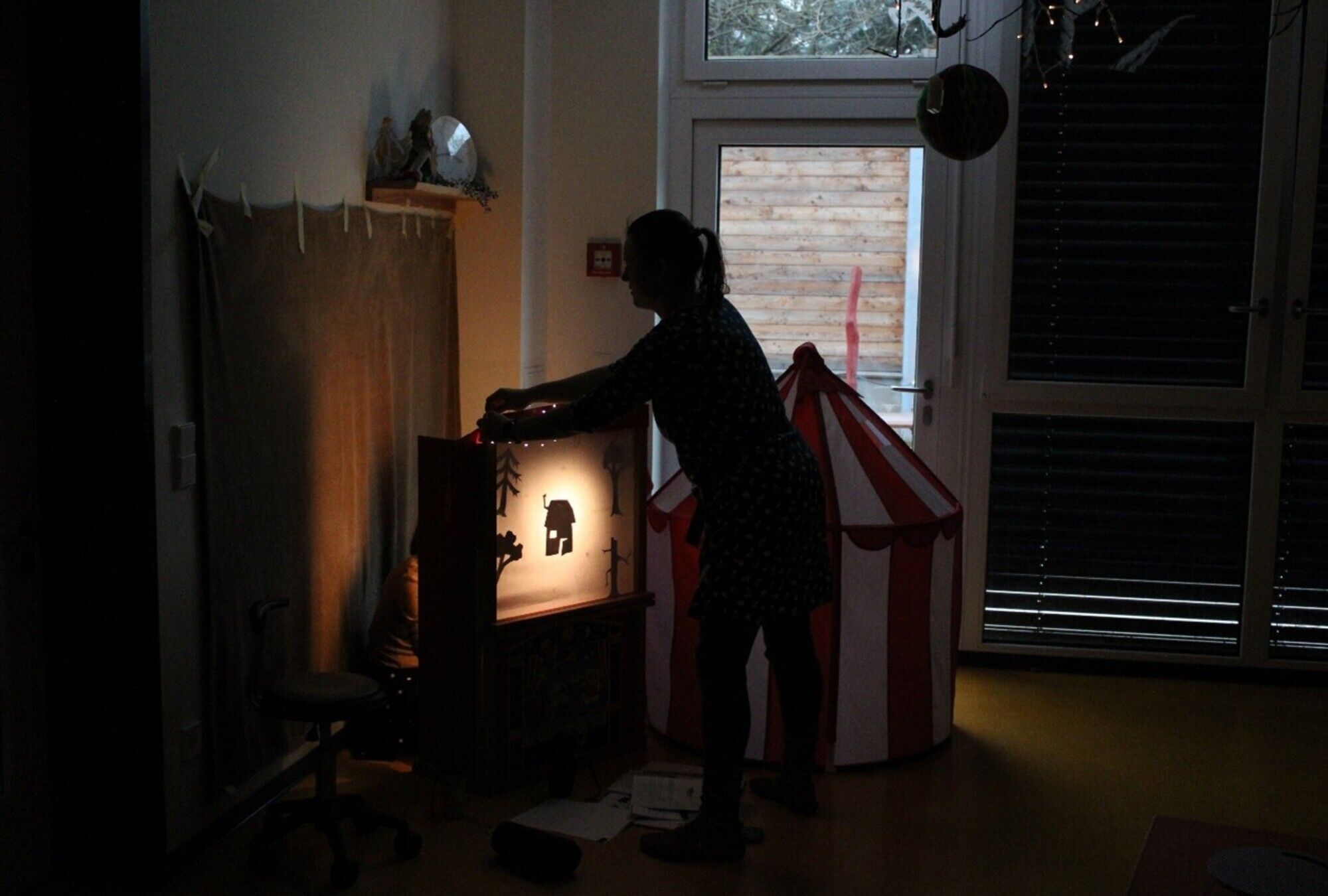 Ein abgedunkelter Raum mit einer hinterleuchteten Theaterwand.