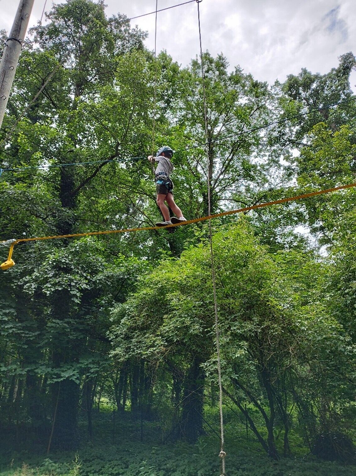 ein Kind balanciert auf einem hohen Seil im Baum