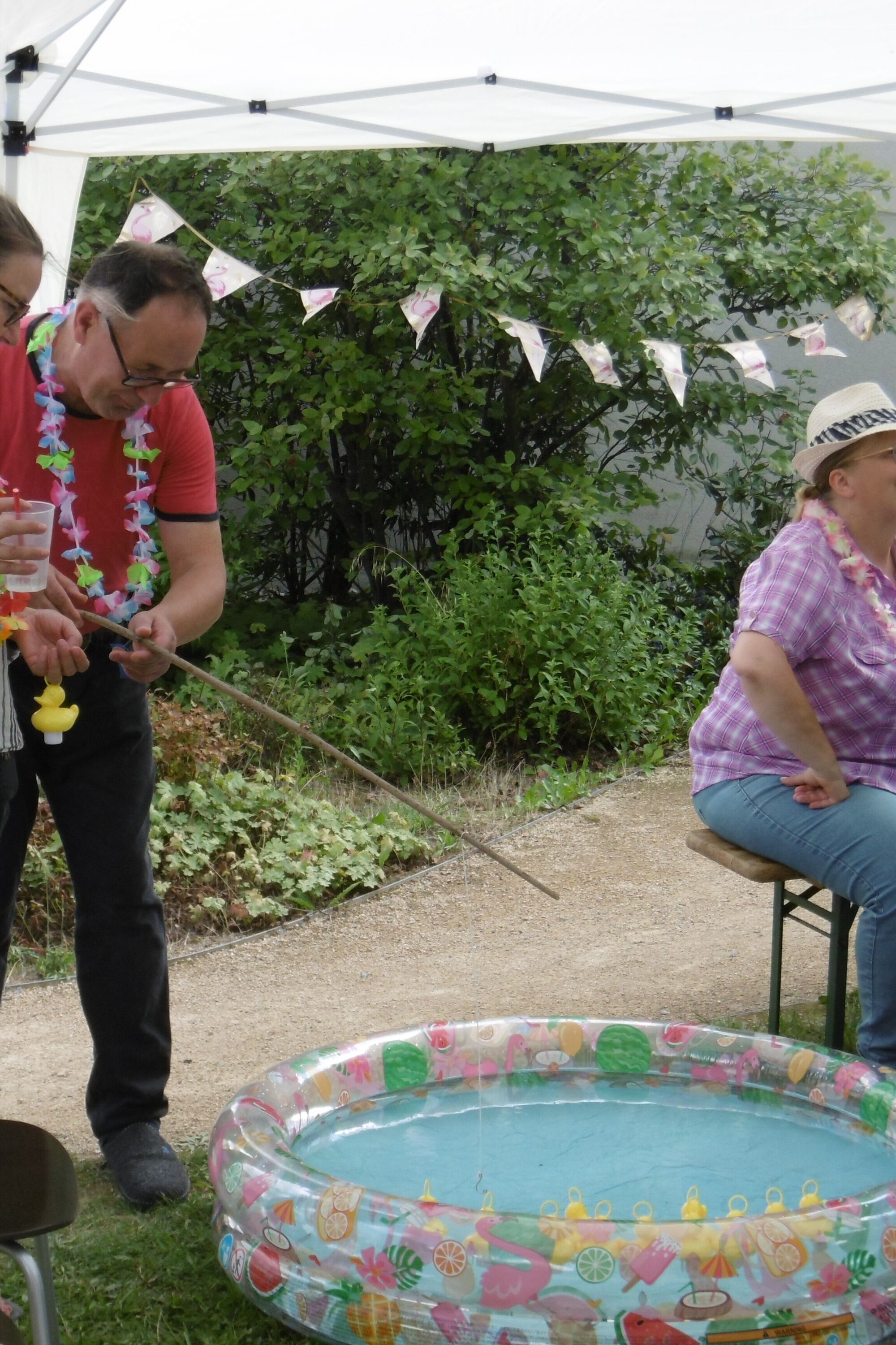 Ein Mann steht an einem kleinen Wasserbassin und angelt Plastikenten