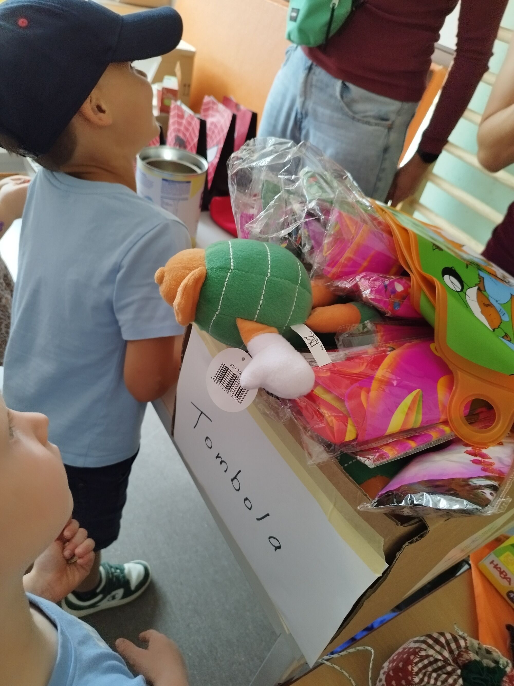 Ein Kind steht vor einem Tisch mit Tombola-Preisen