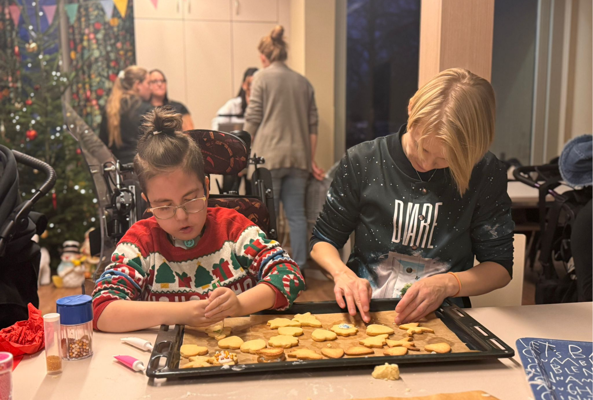 Zwei Menschen verzieren gebackene Plätzchen
